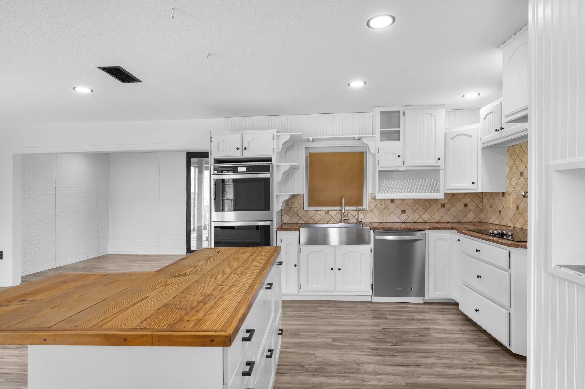 Kitchen with wooden counters, white cabinets, a center island, stainless steel appliances, and recessed lighting