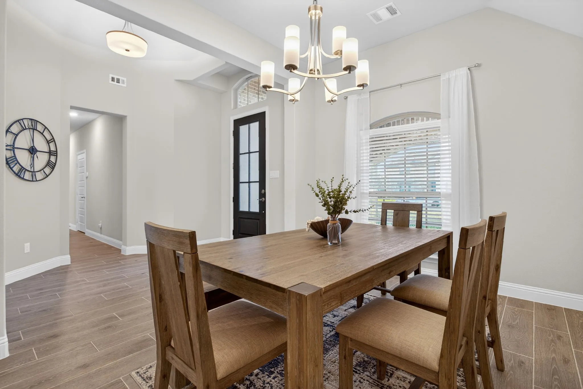 Wood-look tile floors keep maintenance easy. Formal dining at the front of the home; hallway leads to the downstairs guest bedroom and bathroom.