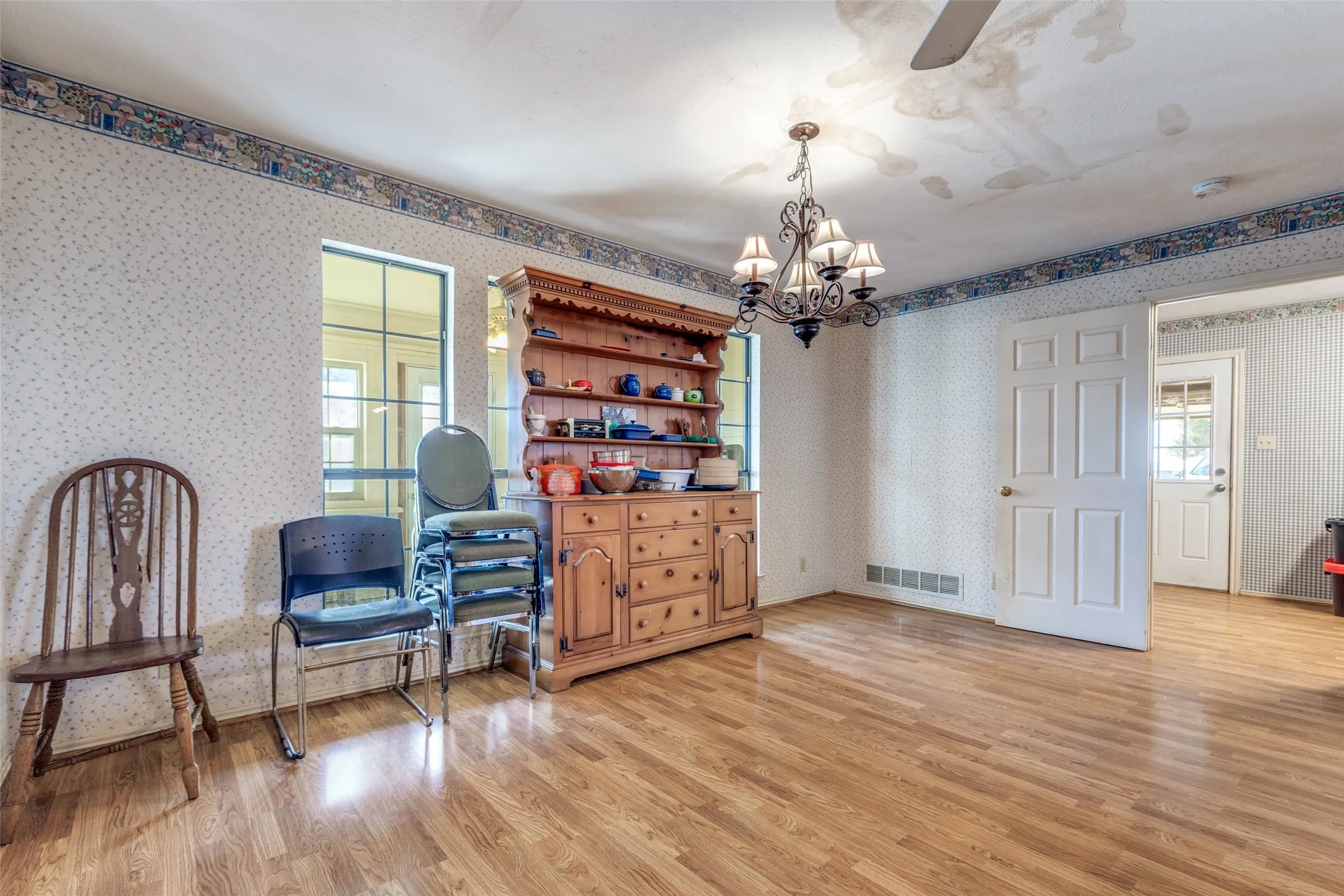 Dining area with a chandelier, light wood finished floors, wallpapered walls, and ceiling fan