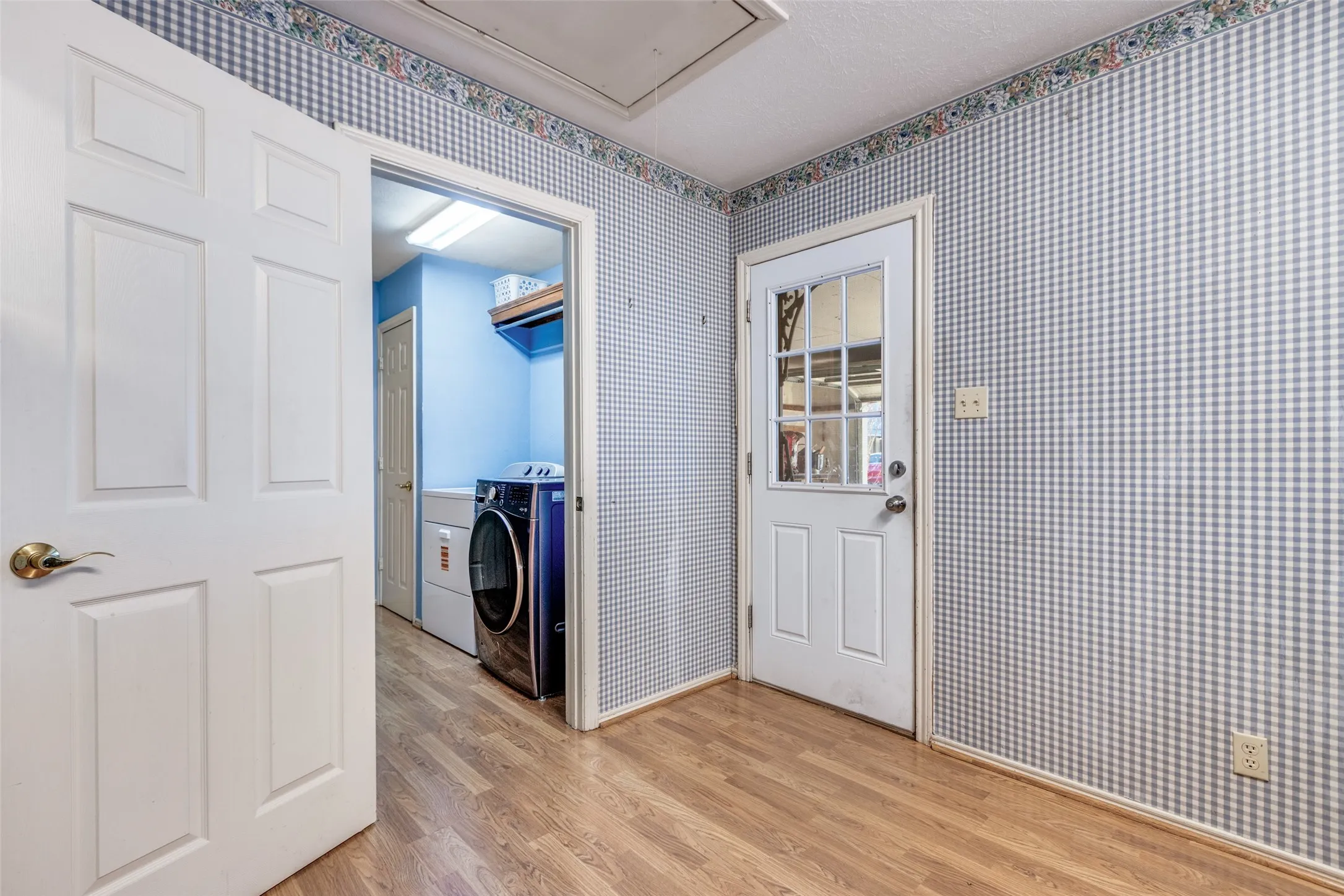 Laundry area featuring wallpapered walls and light wood-type flooring