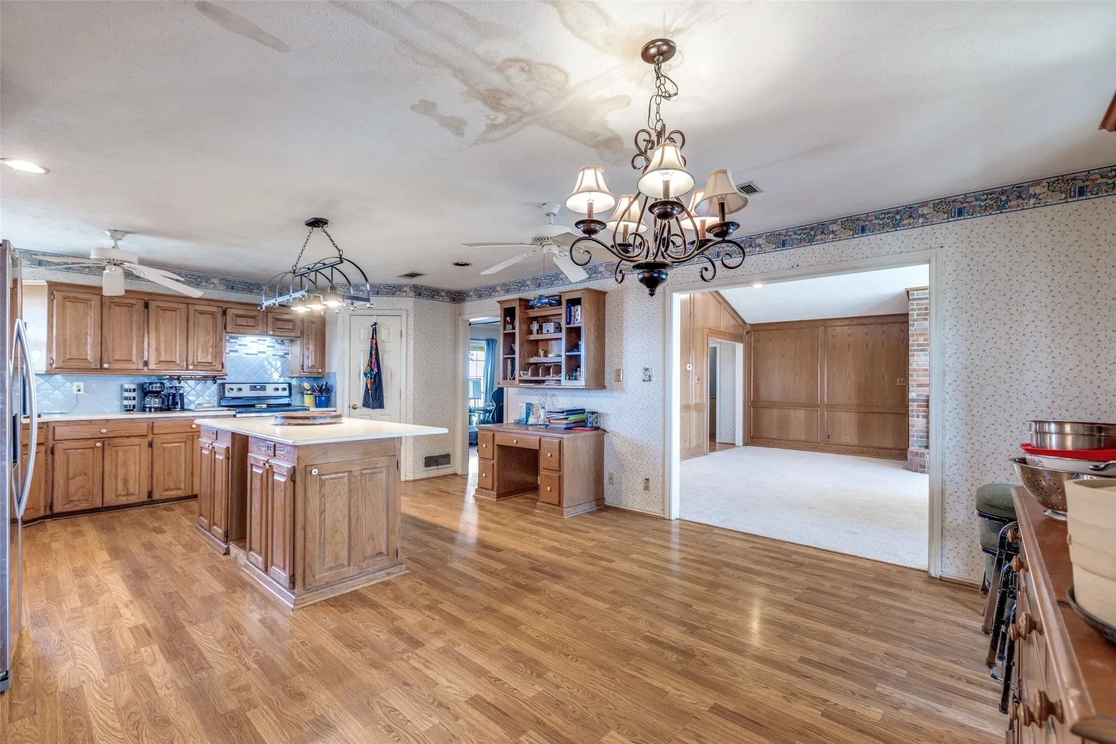 Kitchen featuring wallpapered walls, wood finish cabinets, a center island, light wood finished floors, and open shelves