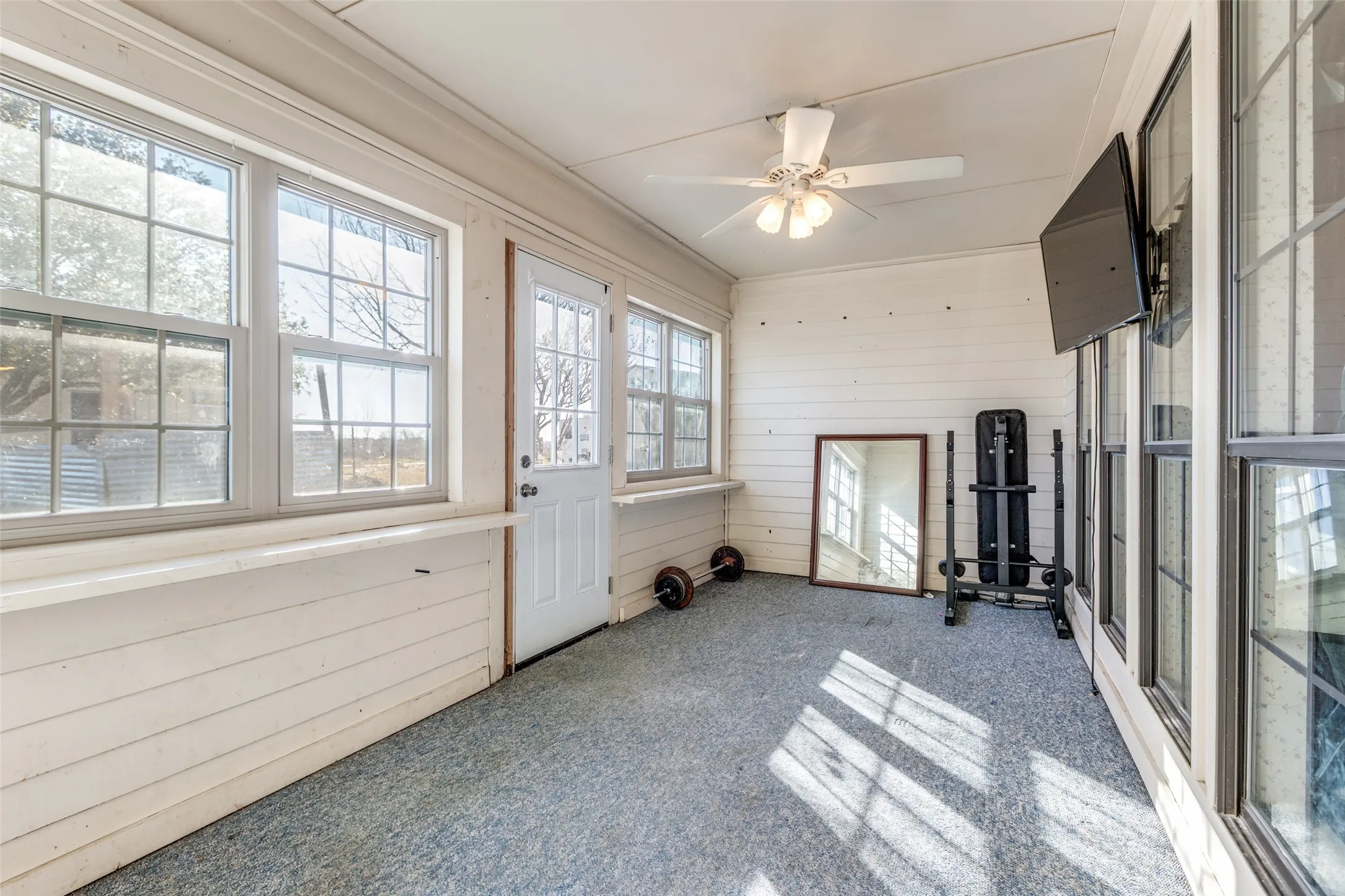 Unfurnished sunroom with a ceiling fan, and wooden walls.