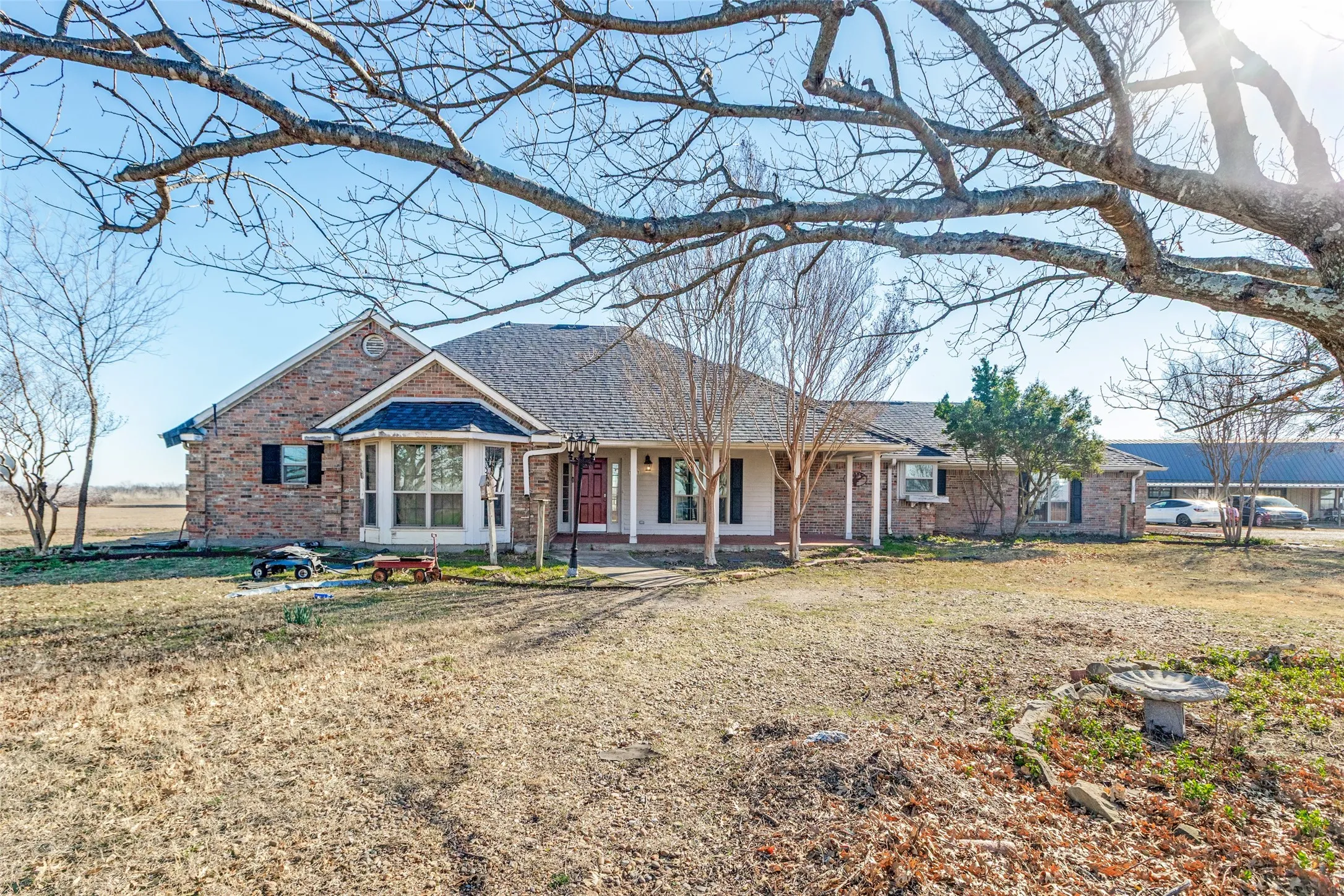 Ranch-style house featuring covered porch, brick siding, a front yard, and roof with shingles