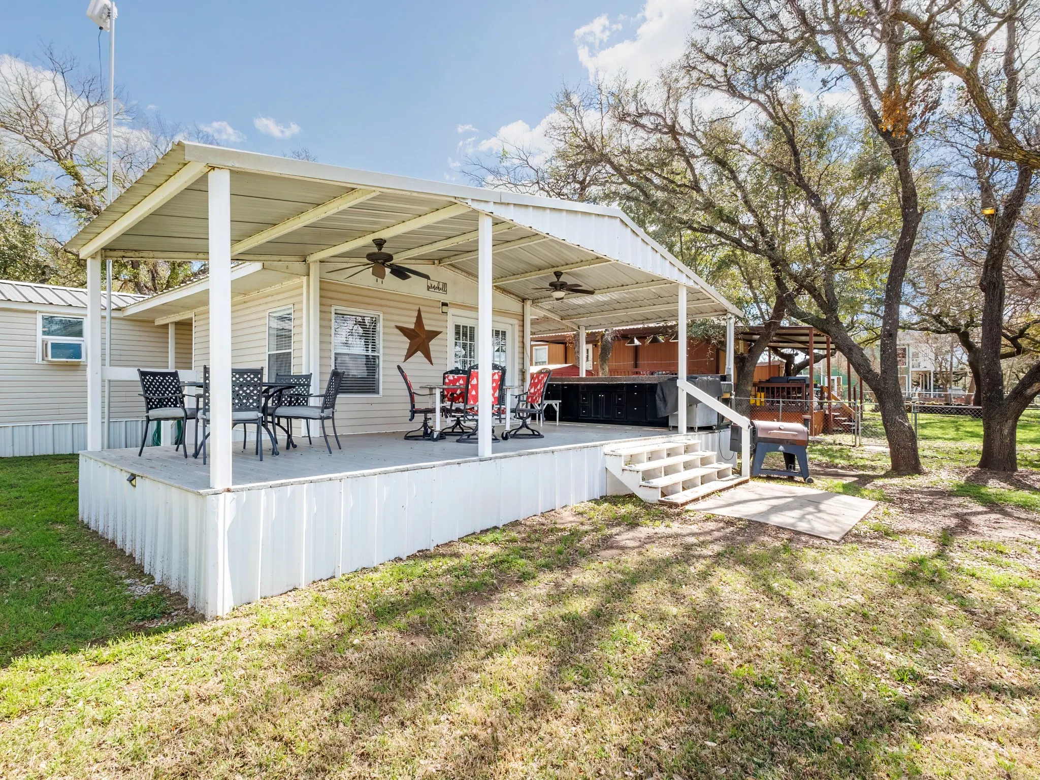 Rear view of property featuring a ceiling fan, a lawn, and a hot tub