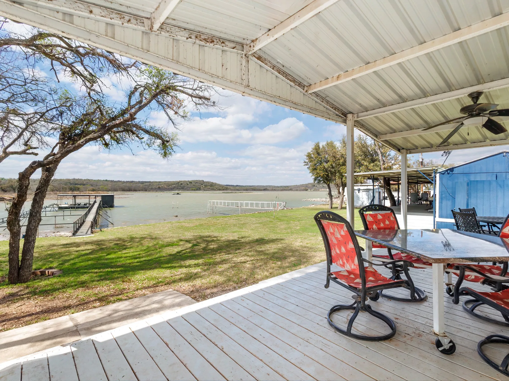 Wooden deck featuring a water view, outdoor dining area, a yard, and ceiling fan
