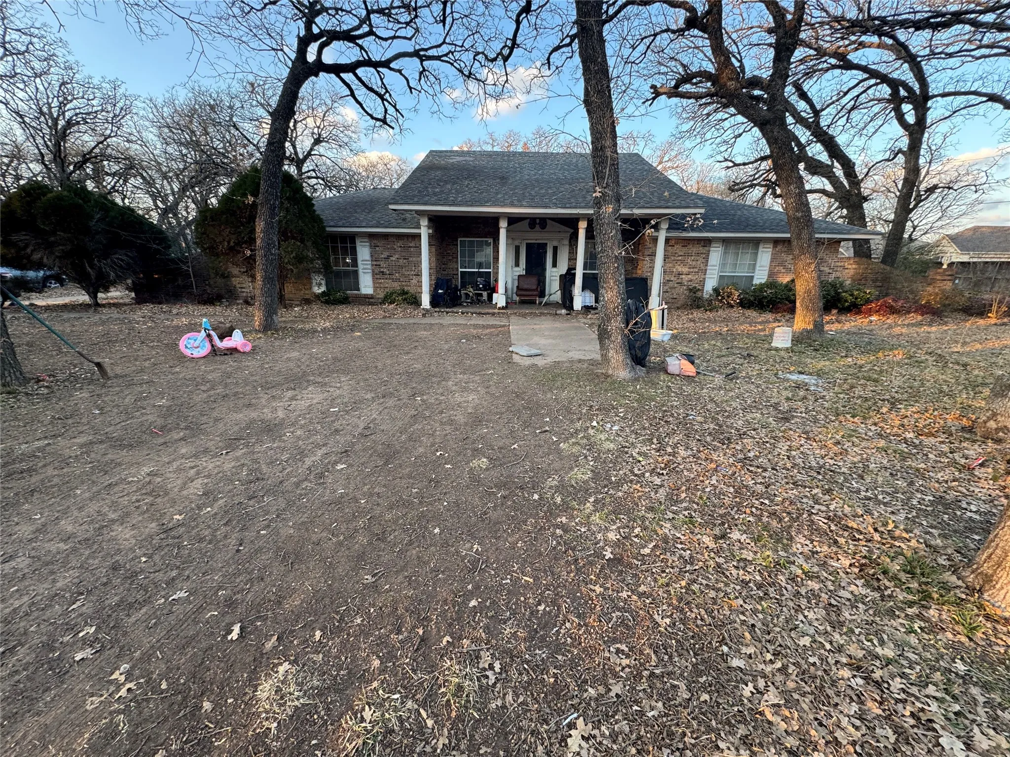 Ranch-style house featuring a porch, a shingled roof, and brick siding