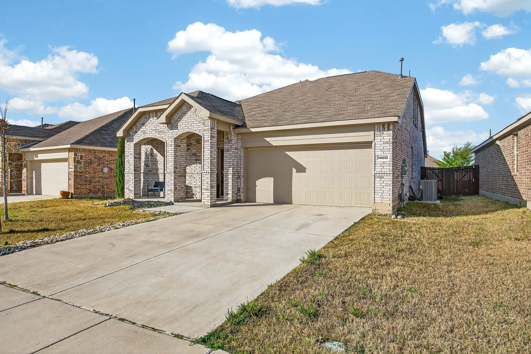 French provincial home with brick siding, a garage, driveway, and a shingled roof