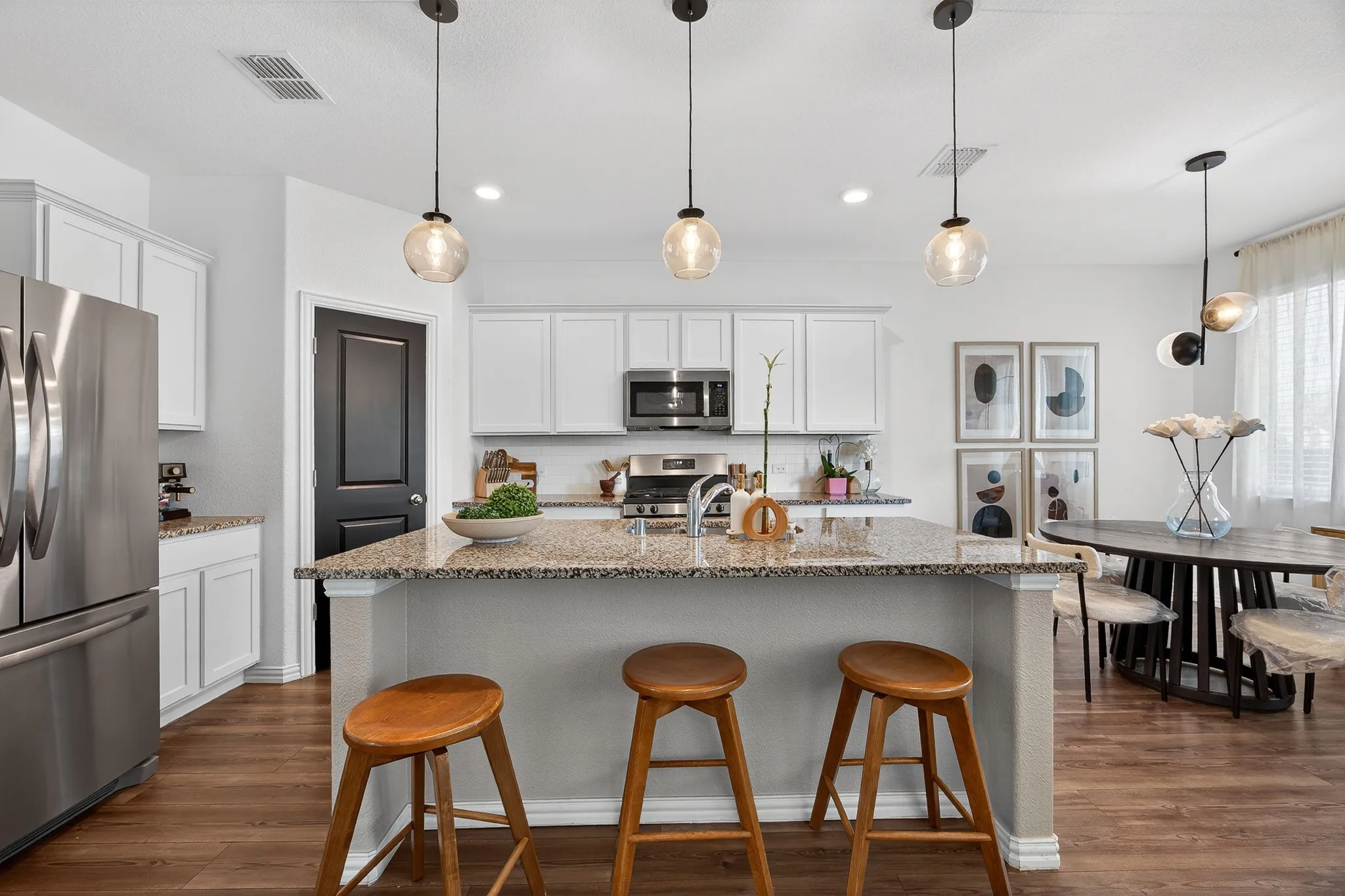 Kitchen featuring stainless steel appliances, light stone counters, a kitchen breakfast bar, white cabinets, and dark wood-type flooring