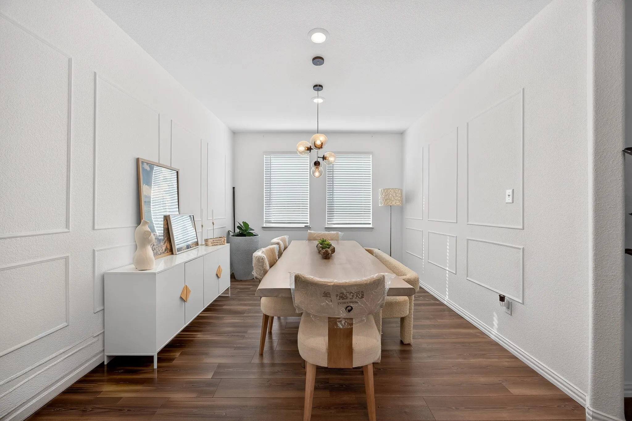 Dining area featuring a decorative wall, dark wood-style floors, and a chandelier