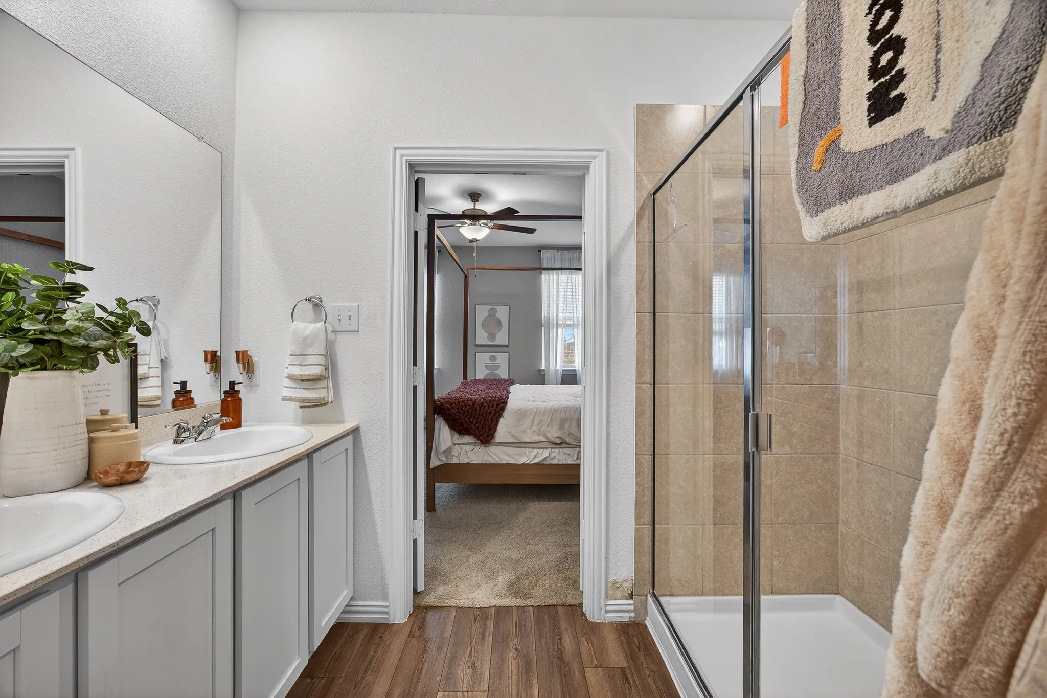 Bathroom featuring ensuite bathroom, dark wood-style floors, a shower stall, and double vanity