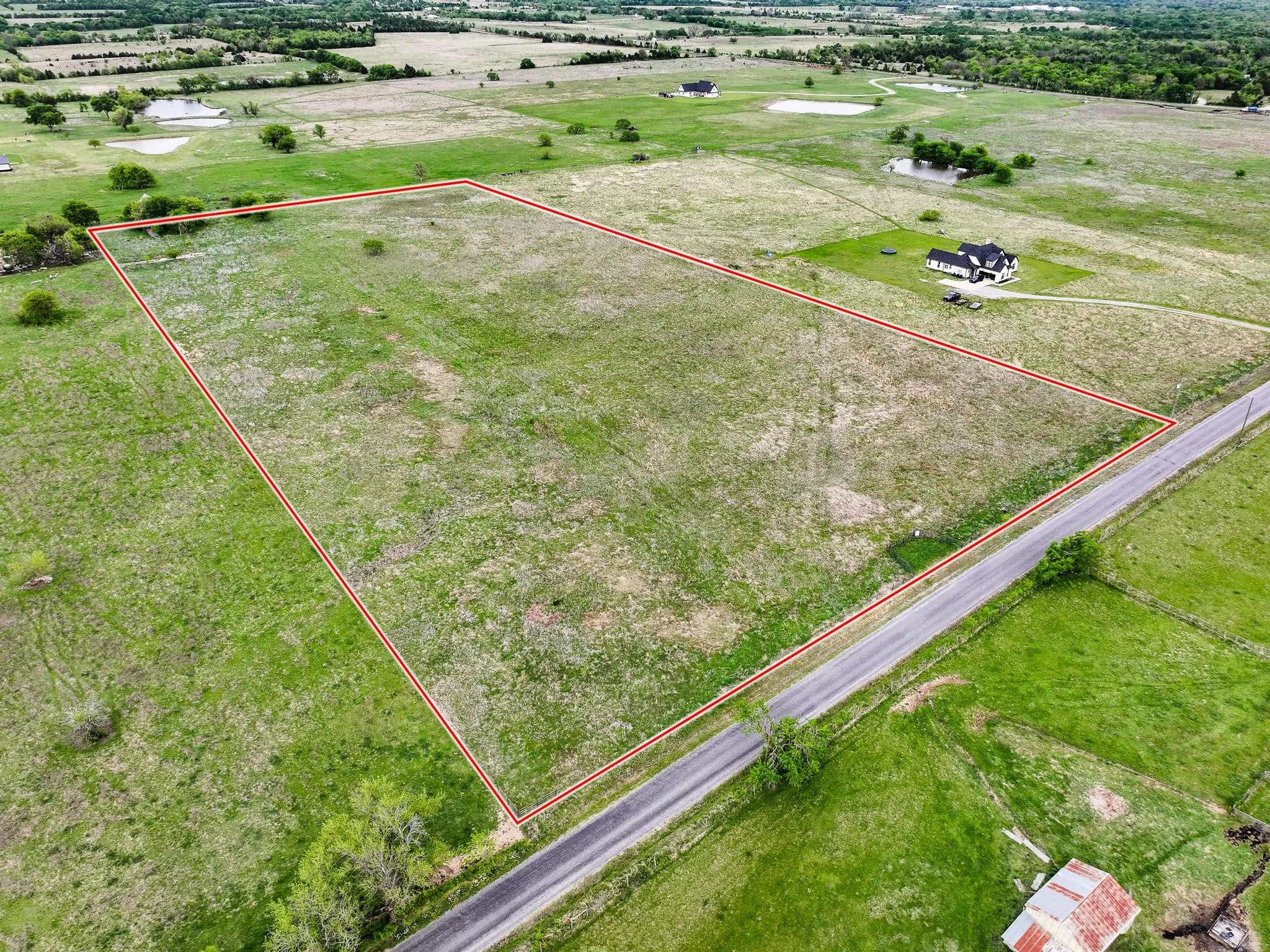 Expansive land parcel featuring a defined boundary, frontage along a paved road, and a predominantly grassed terrain