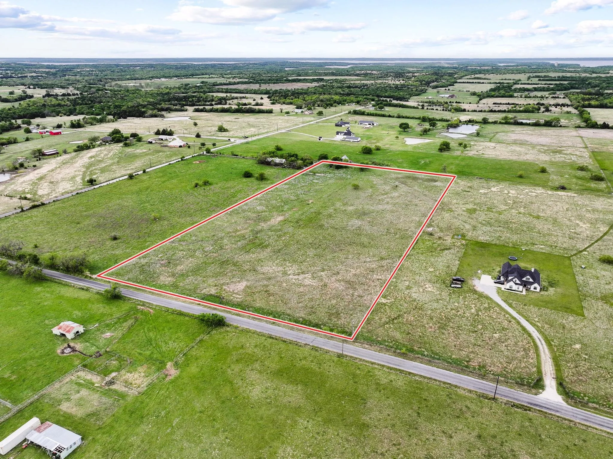 Expansive land parcel featuring open fields and direct road frontage