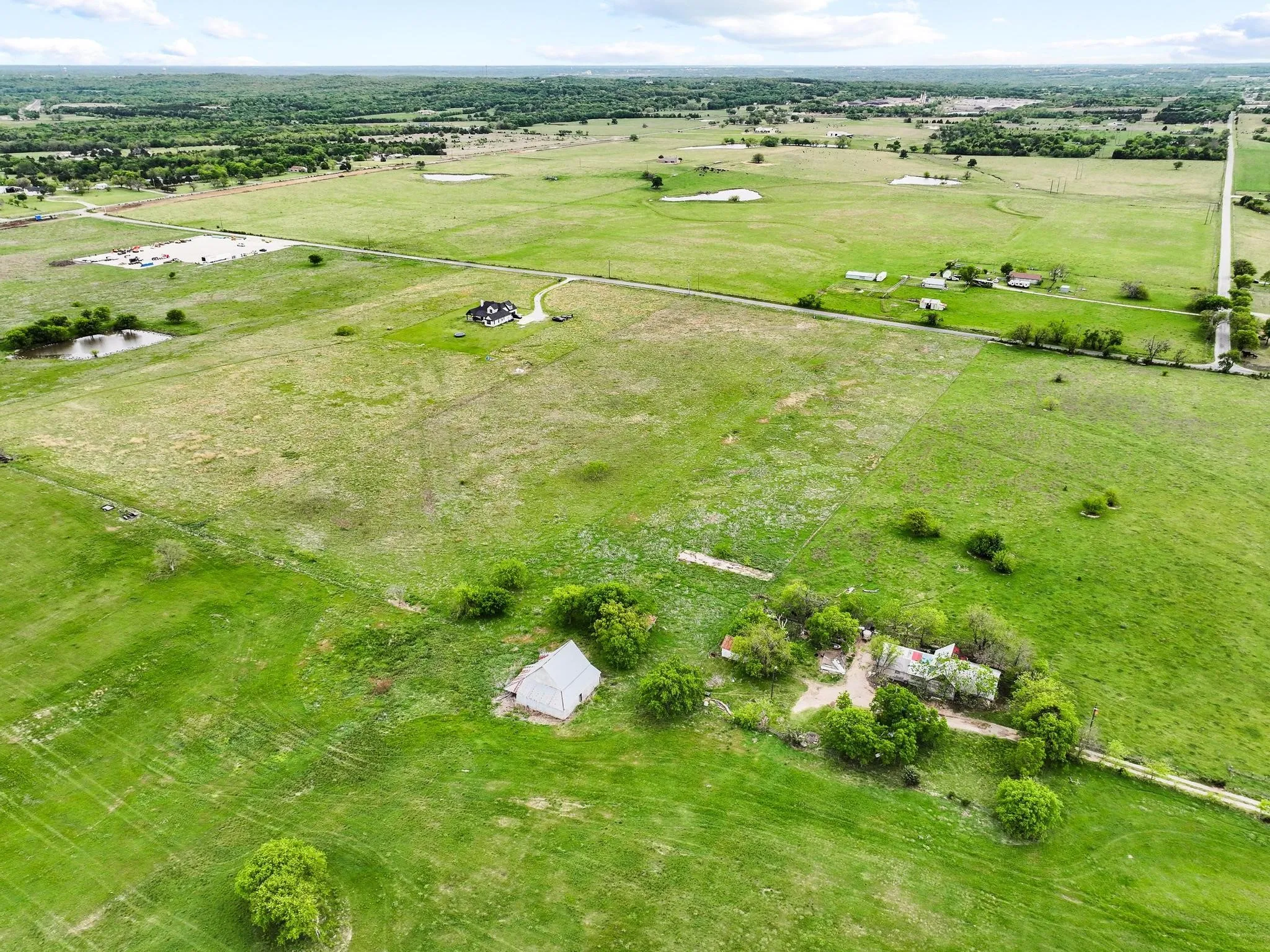 Expansive green acreage featuring multiple outbuildings, two ponds, and established trees