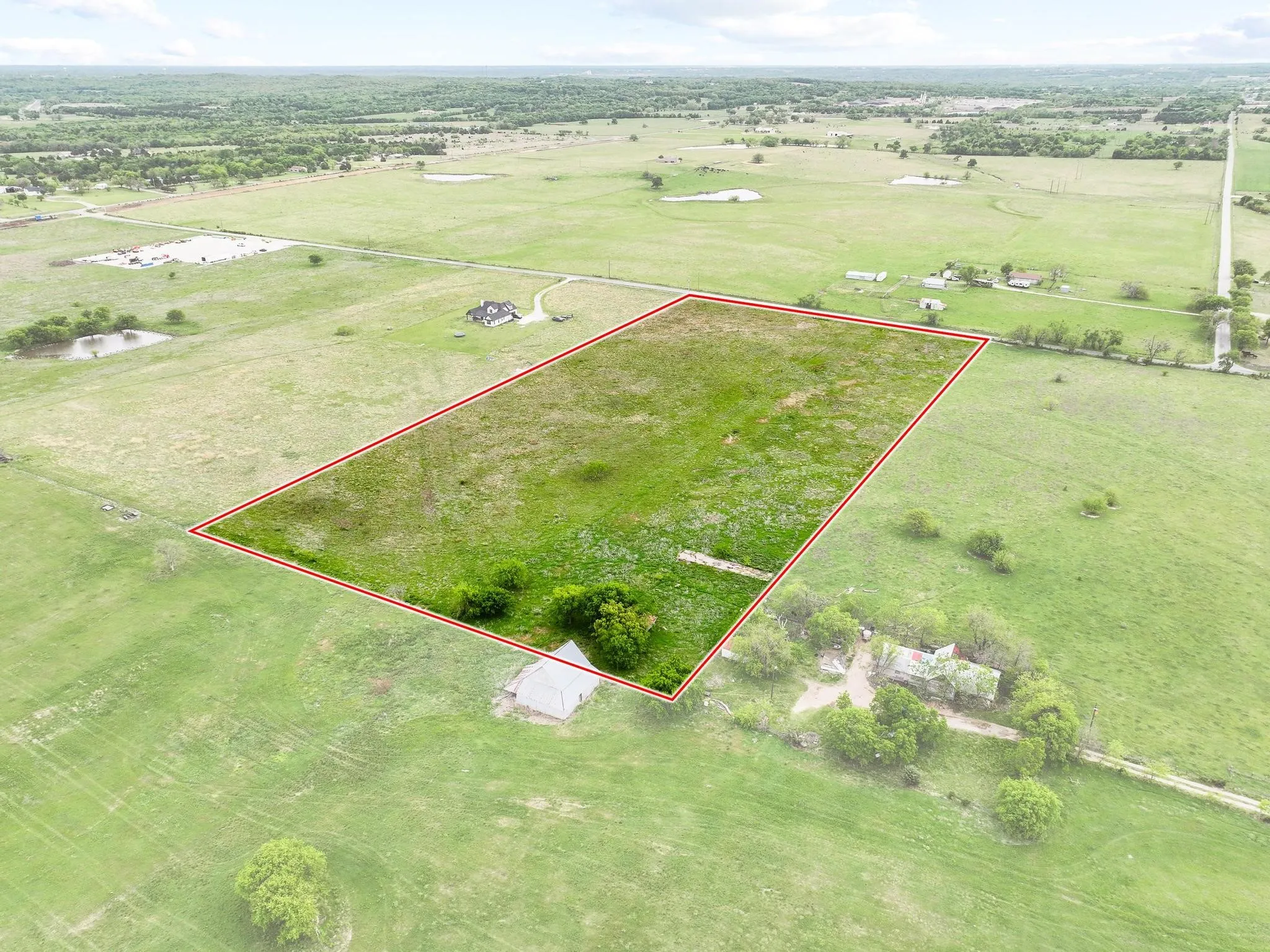 Expansive parcel of land outlined in red, featuring a mix of open fields and scattered trees