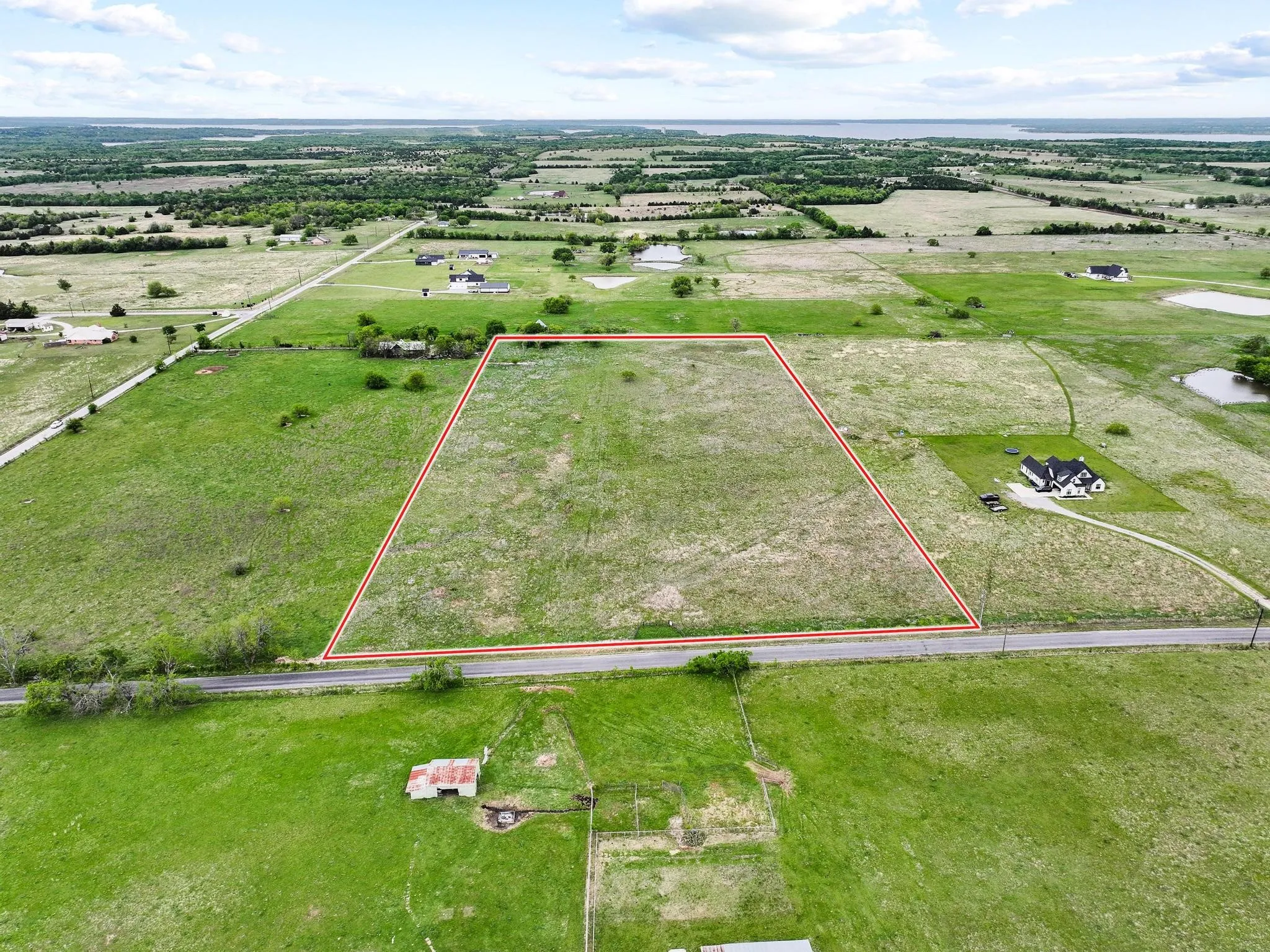 Expansive land parcel featuring a road frontage and surrounding green spaces