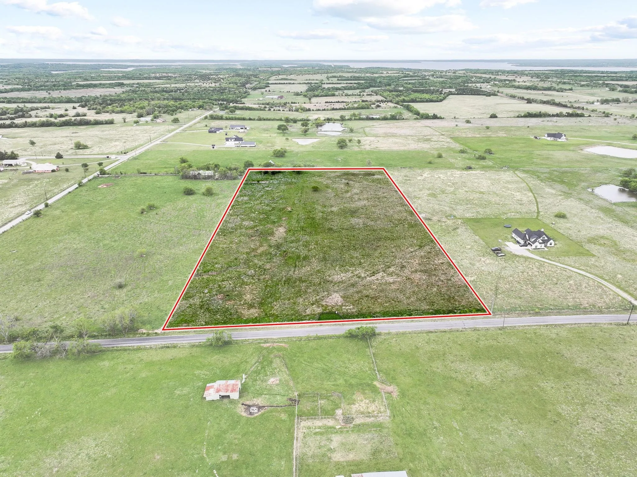 Expansive undeveloped land parcel featuring a clear boundary, direct road frontage, and varied grassland terrain