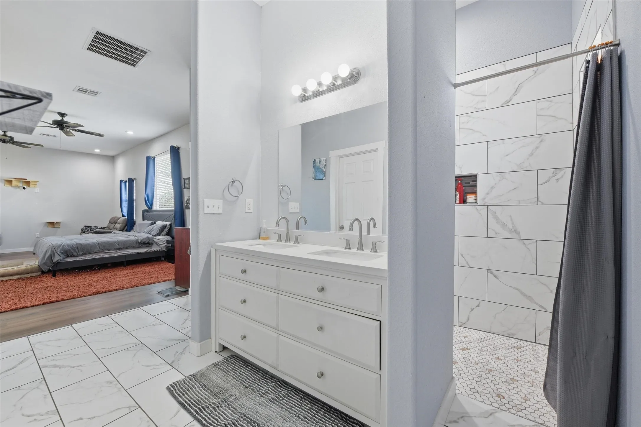Ensuite bathroom featuring light marble finish flooring, a stall shower, double vanity, and ceiling fan