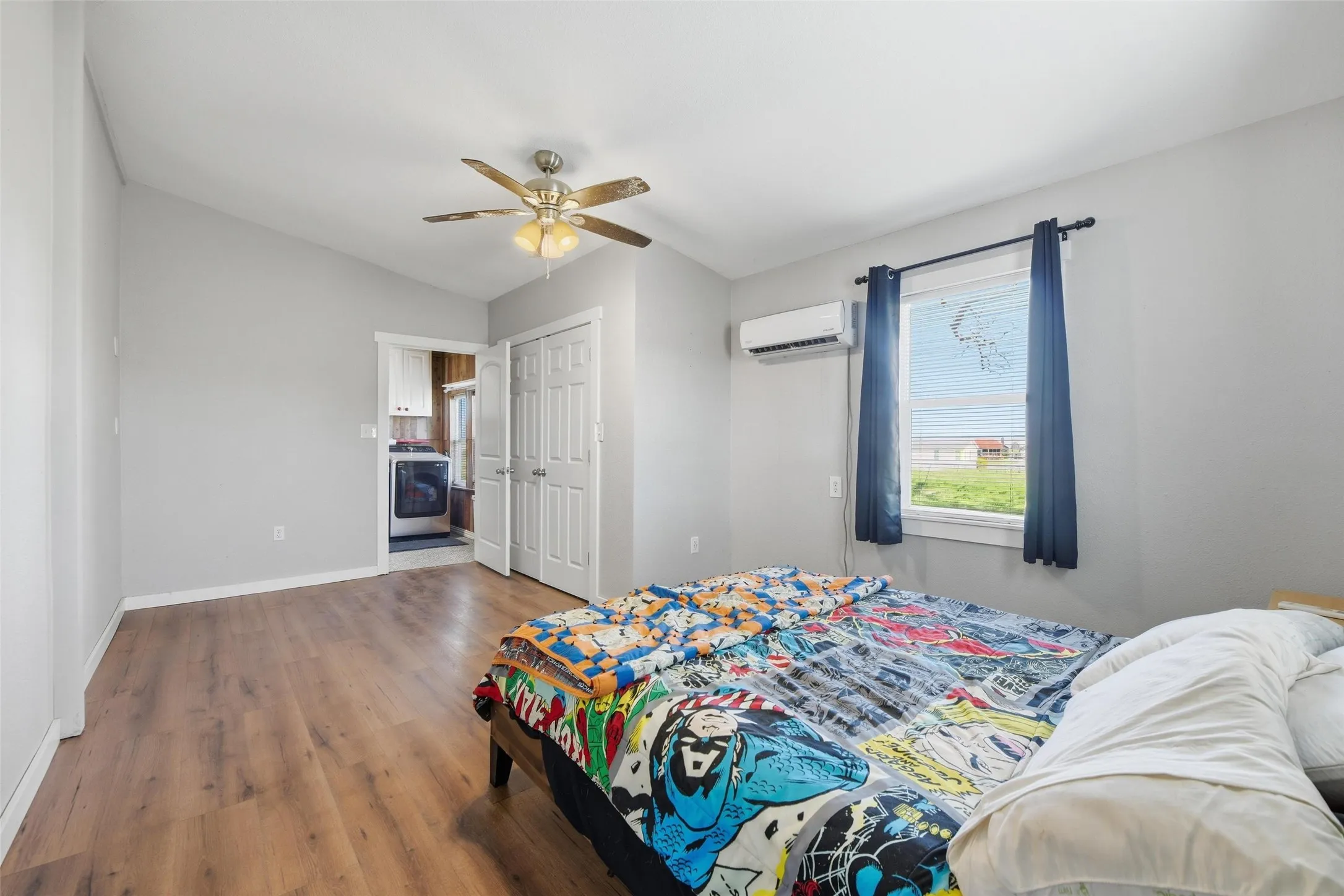 Bedroom with wood finished floors, a ceiling fan, a closet, vaulted ceiling, and washer / dryer