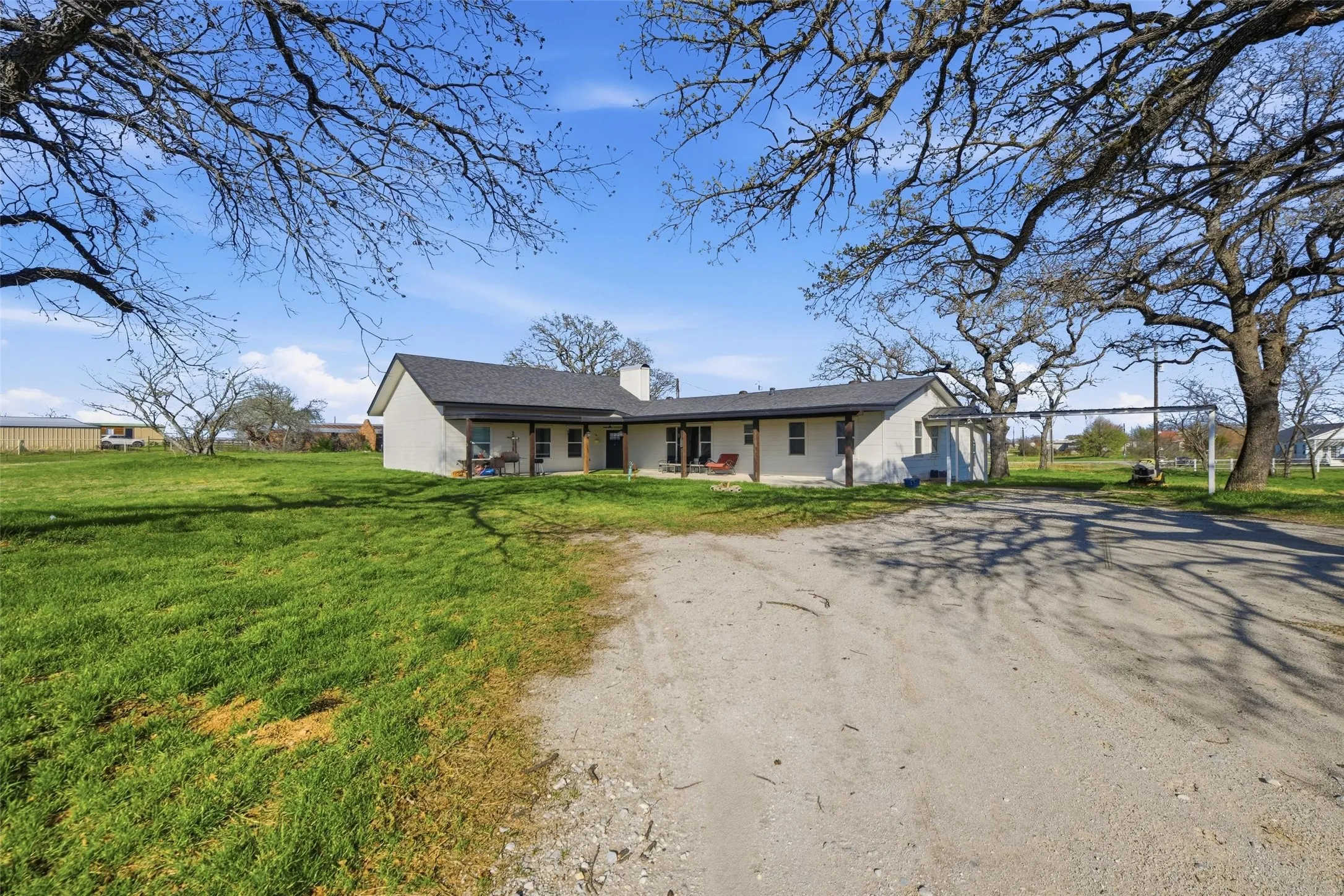 Ranch-style home with driveway, a front lawn, a chimney, and a patio area