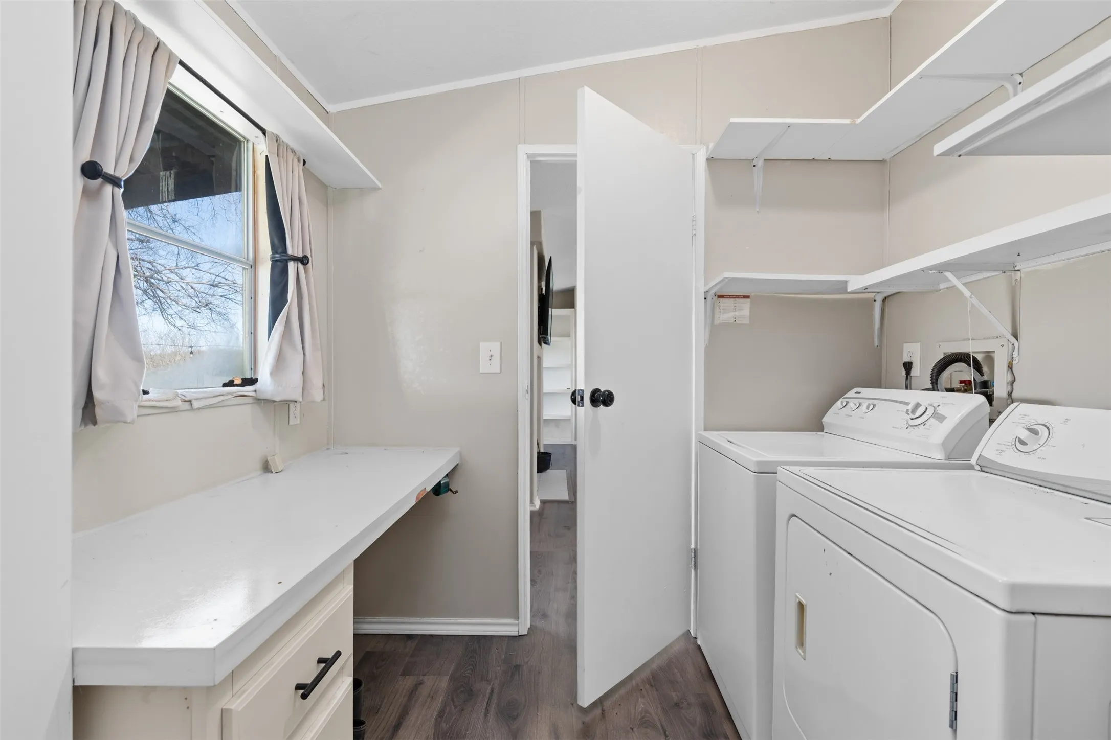 Laundry area featuring dark wood-type flooring, ornamental molding, and washer and clothes dryer