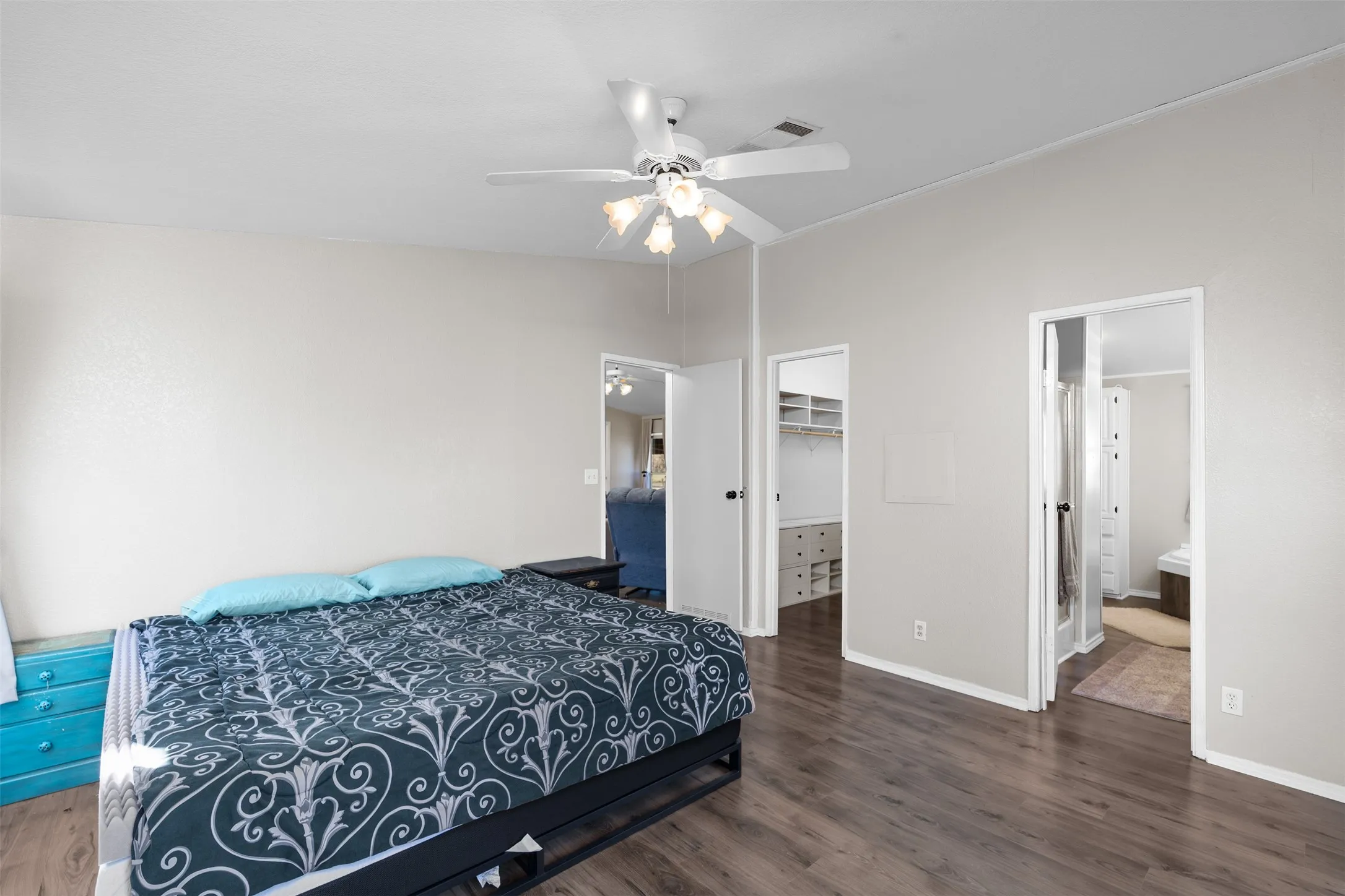 Bedroom featuring a walk in closet, dark wood-style flooring, and ceiling fan