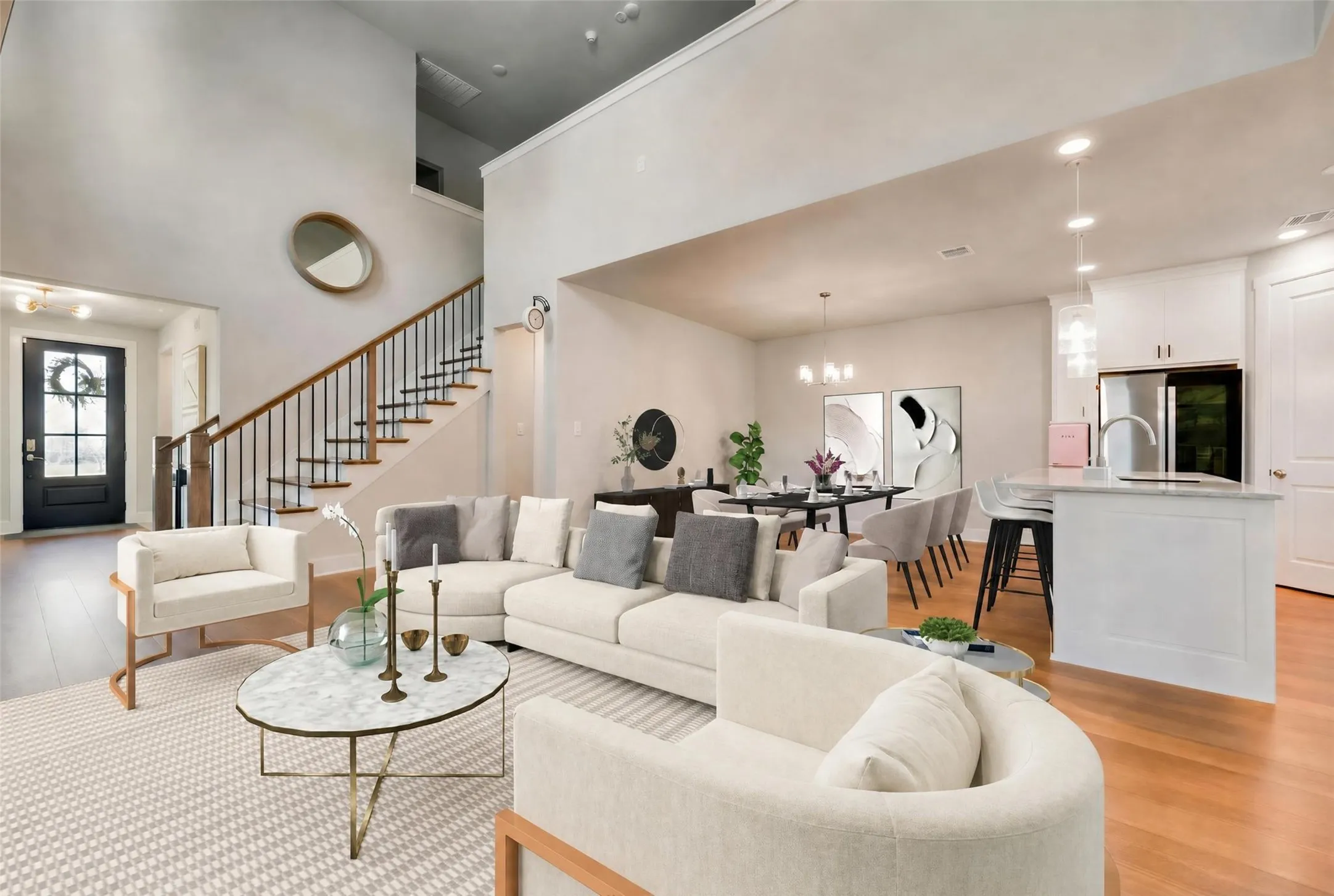 Open-concept living area featuring high ceilings, wood-finish flooring, and a contemporary staircase with iron balusters