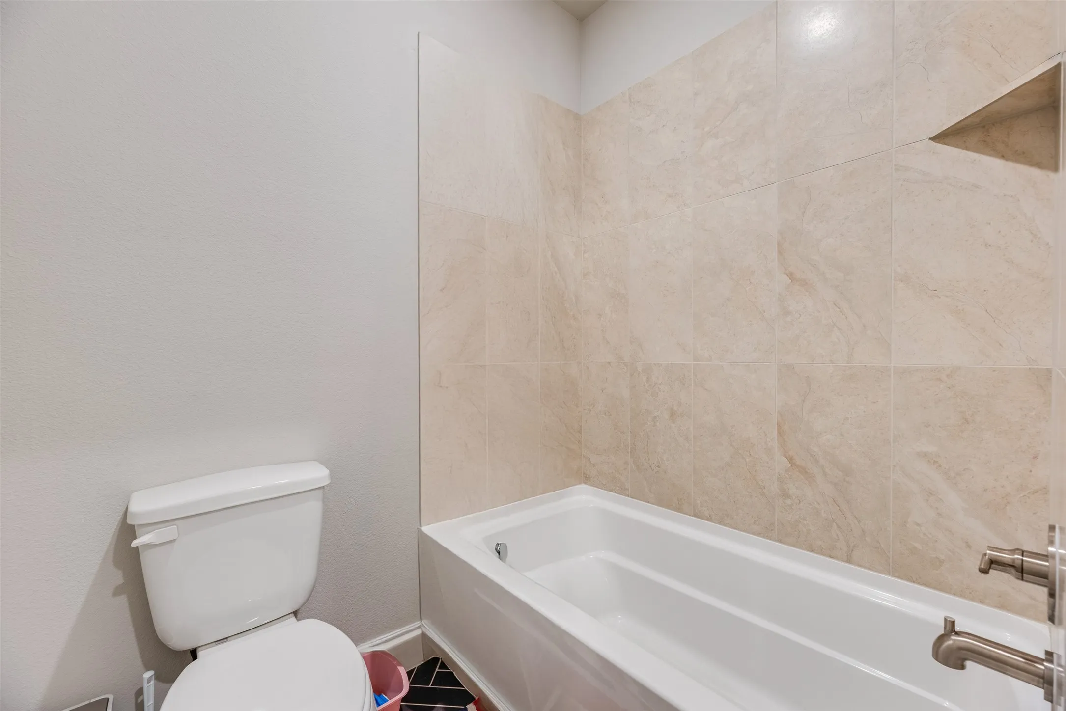 Bathtub and shower surround featuring large-format tile, a built-in shower niche, and brushed nickel fixtures