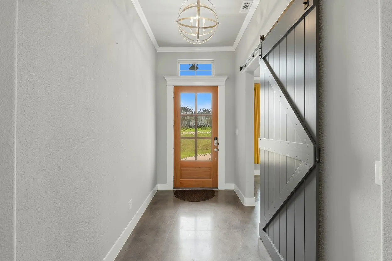 Entryway featuring a wood-panel door with glass inserts, a transom window, and a modern orb chandelier