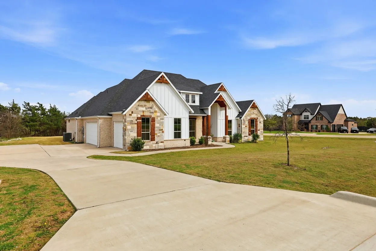 Curb appeal featuring stone and vertical siding accents, dark roof shingles, and a concrete driveway