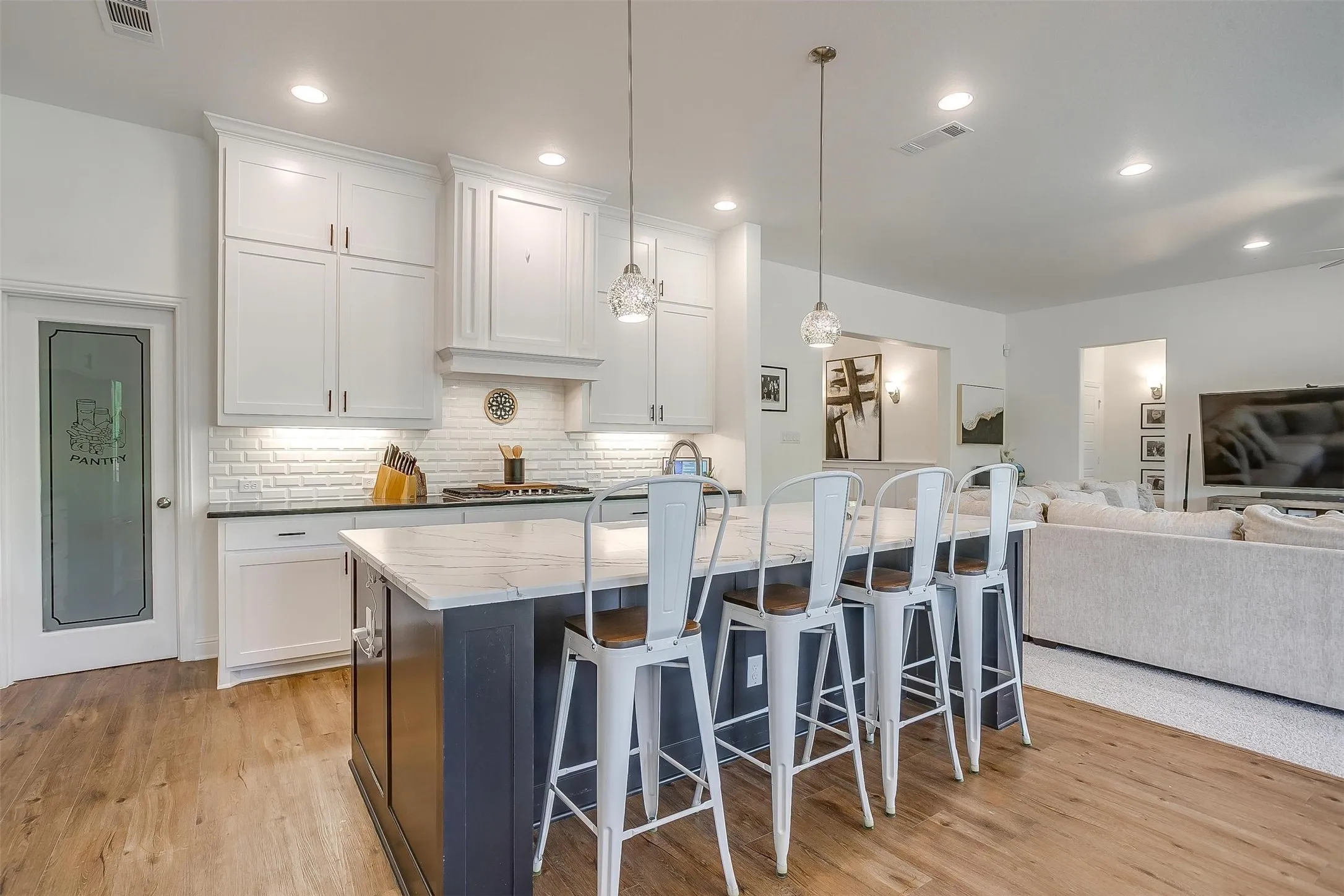 The kitchen also has a spacious island complete with outlets for your food-prep appliances.  Gorgeous pendant lighting accent the space.  The walk-in pantry has a gorgeous engraved doorway.  Note the built-in cabinets above go to the ceiling for additional storage.  The backsplash is an elegant custom tile.  The gas cook-top is perfect for chef-inspired dishes.