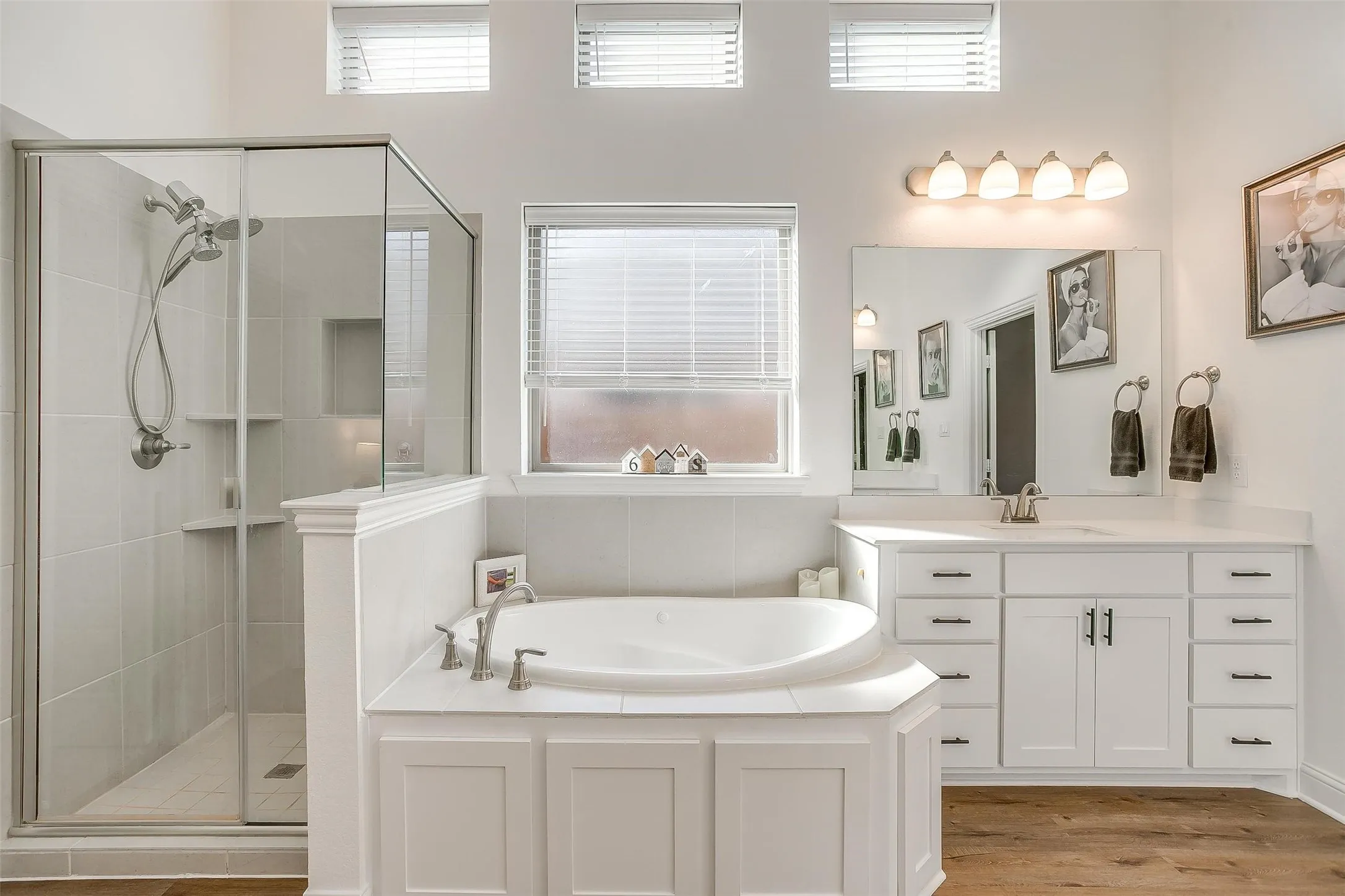 Walk-in shower with built-in shelving and dual rain-shower heads, garden tub for relaxation, natural lighting from frosted window and lateral windows above.  A truly elegant primary bath!