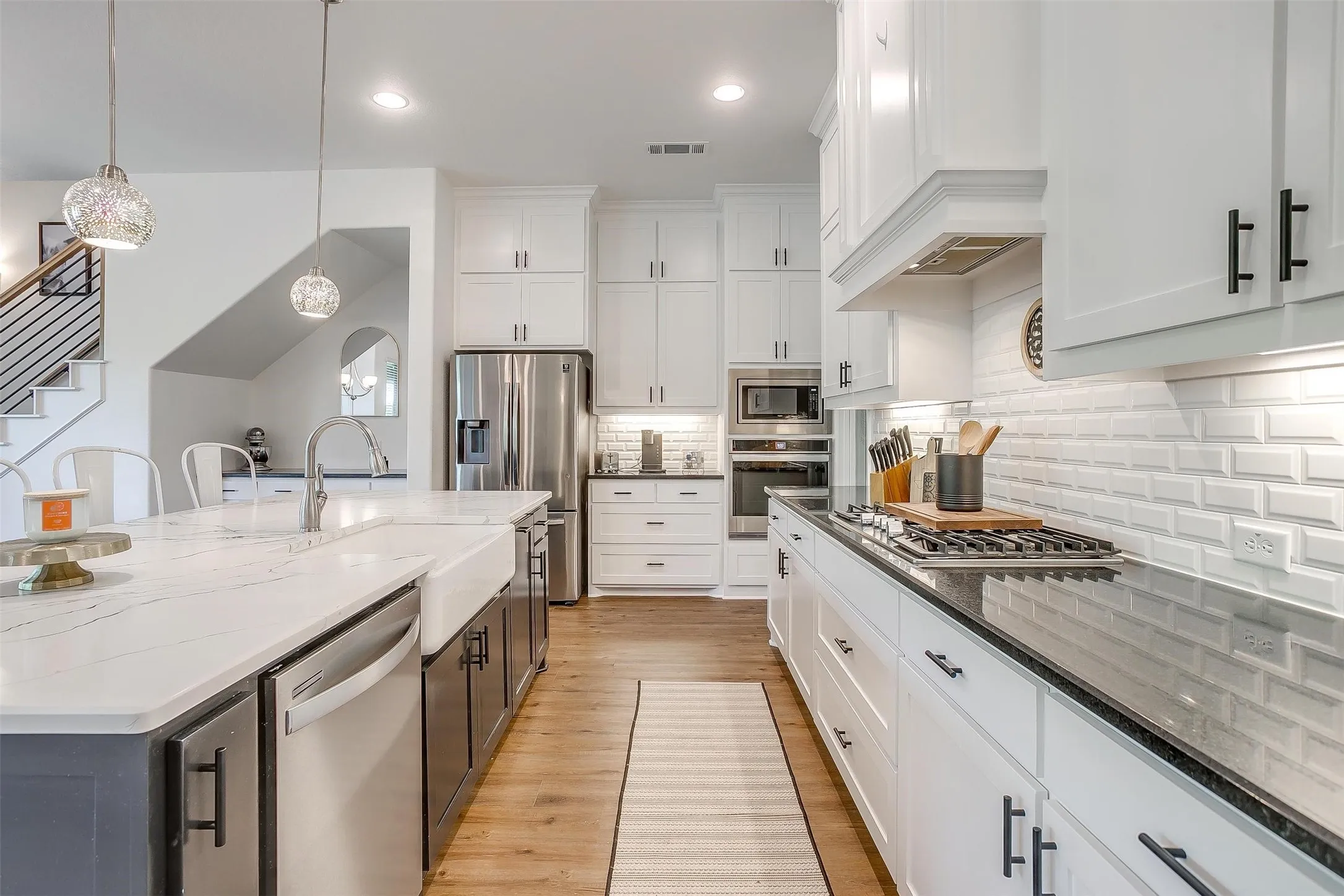 View of the kitchen and stainless appliances, farm sink, pull-down sprayer faucet, 5-burner gas cook-top with vented​​‌​​​​‌​​‌‌​‌‌​​​‌‌​‌​‌​‌​​​‌​​ hood.