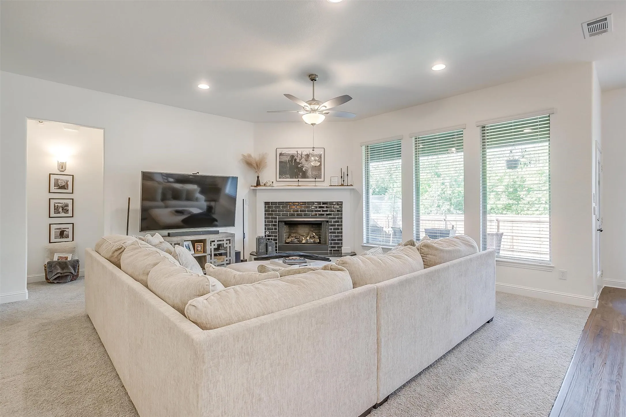 The primary living area with lots of natural lighting from the windows as well as recessed lighting from the ceiling.  Plush carpeting adds to the cozy environment, centered by the brick fireplace, with wood mantel and marble hearth.