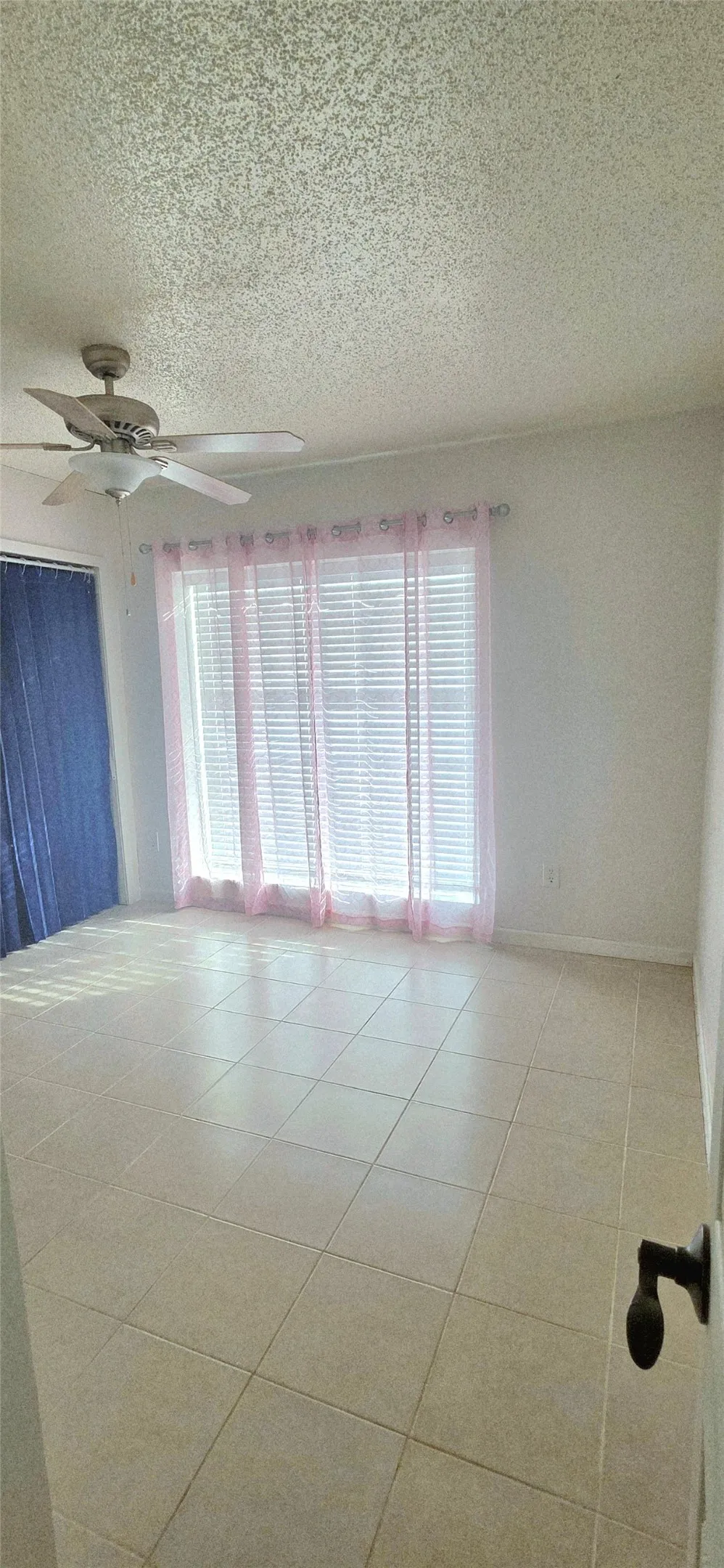 Unfurnished room featuring a ceiling fan, a textured ceiling, and plenty of natural light