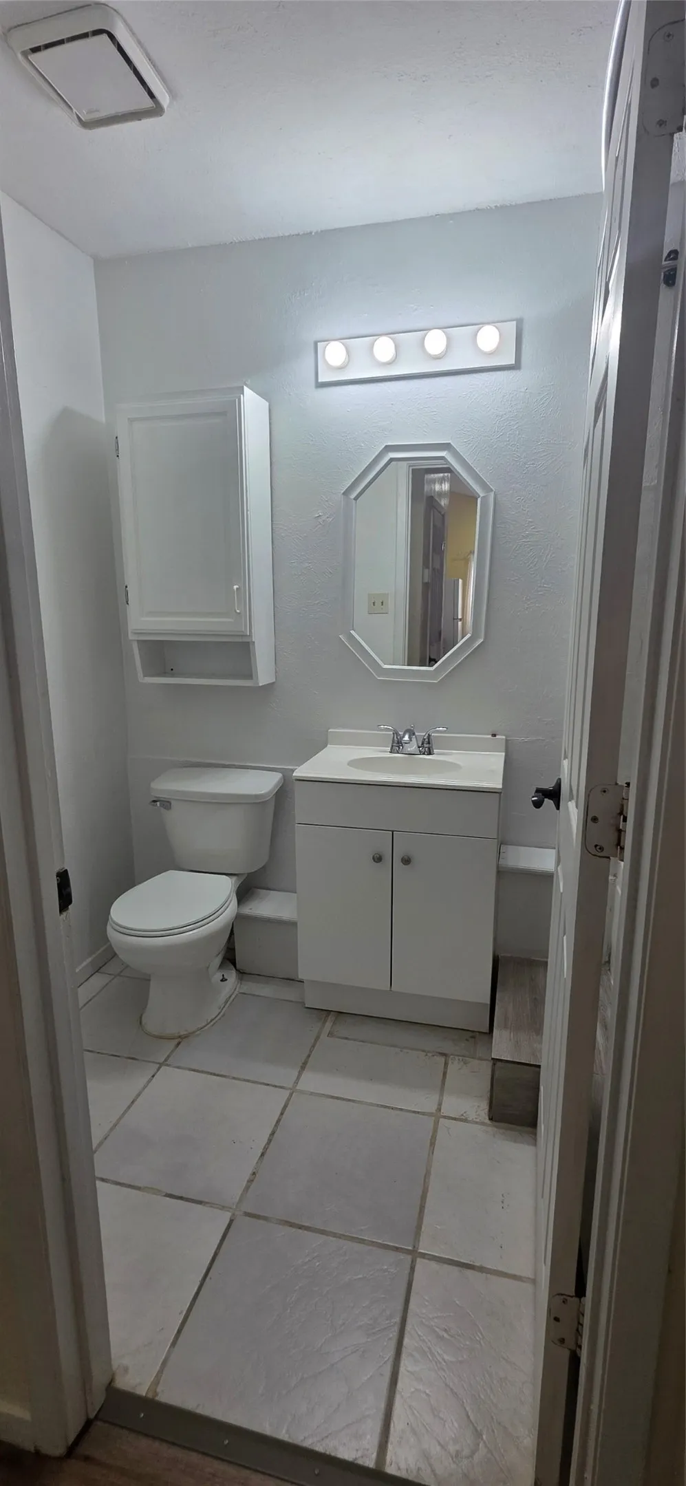 Half bath with vanity and light tile patterned flooring