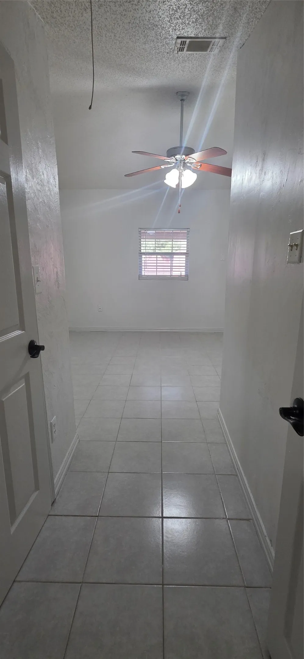Empty room featuring light tile patterned floors and a ceiling fan