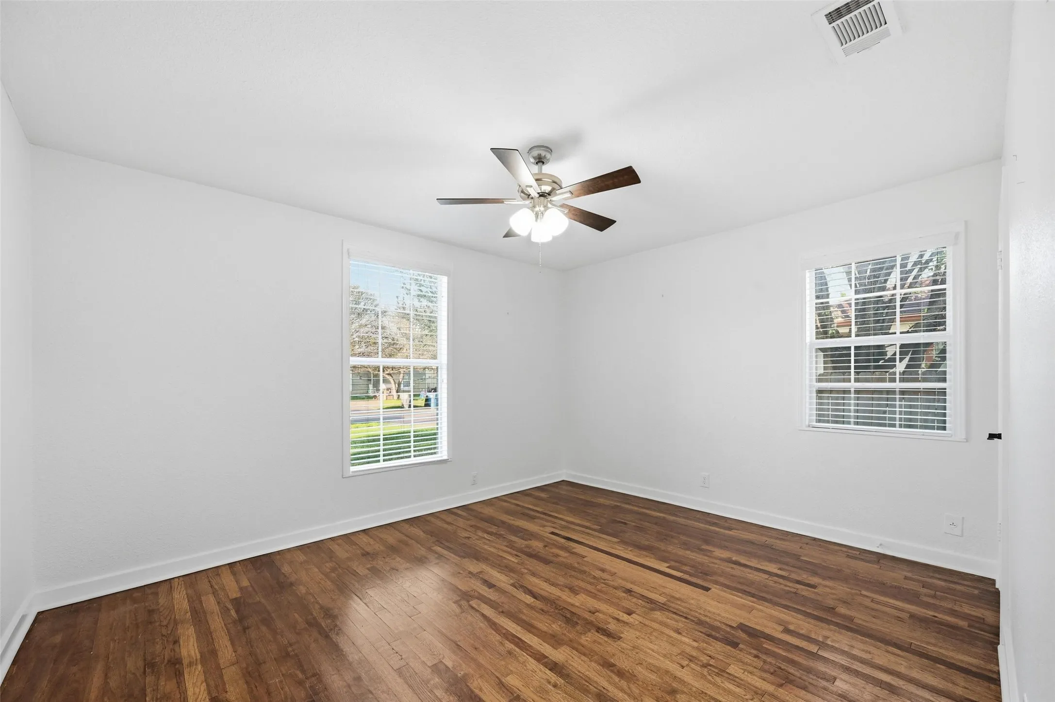 Unfurnished room featuring dark wood-type flooring and ceiling fan