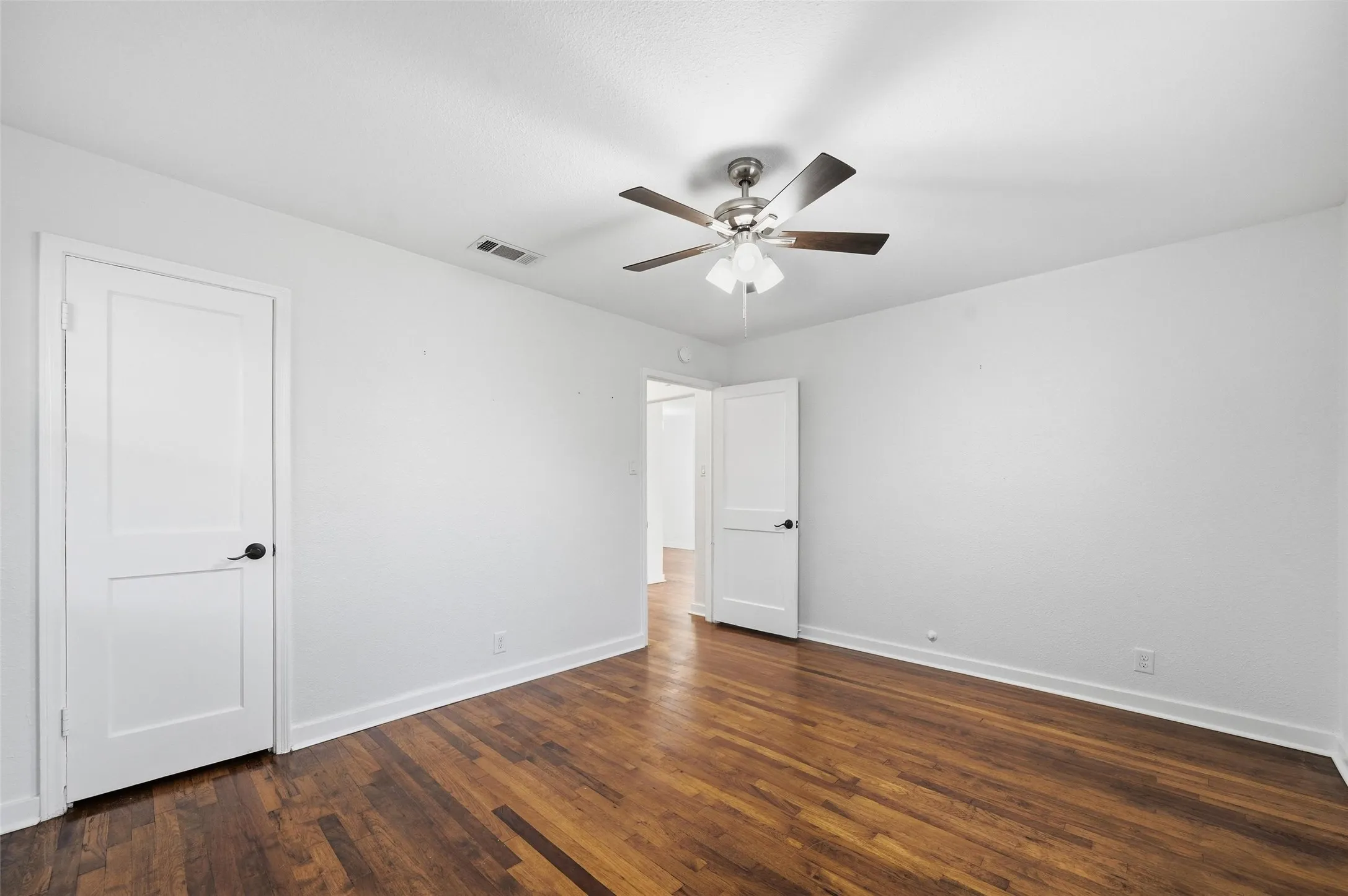 Unfurnished bedroom with dark wood-type flooring and ceiling fan