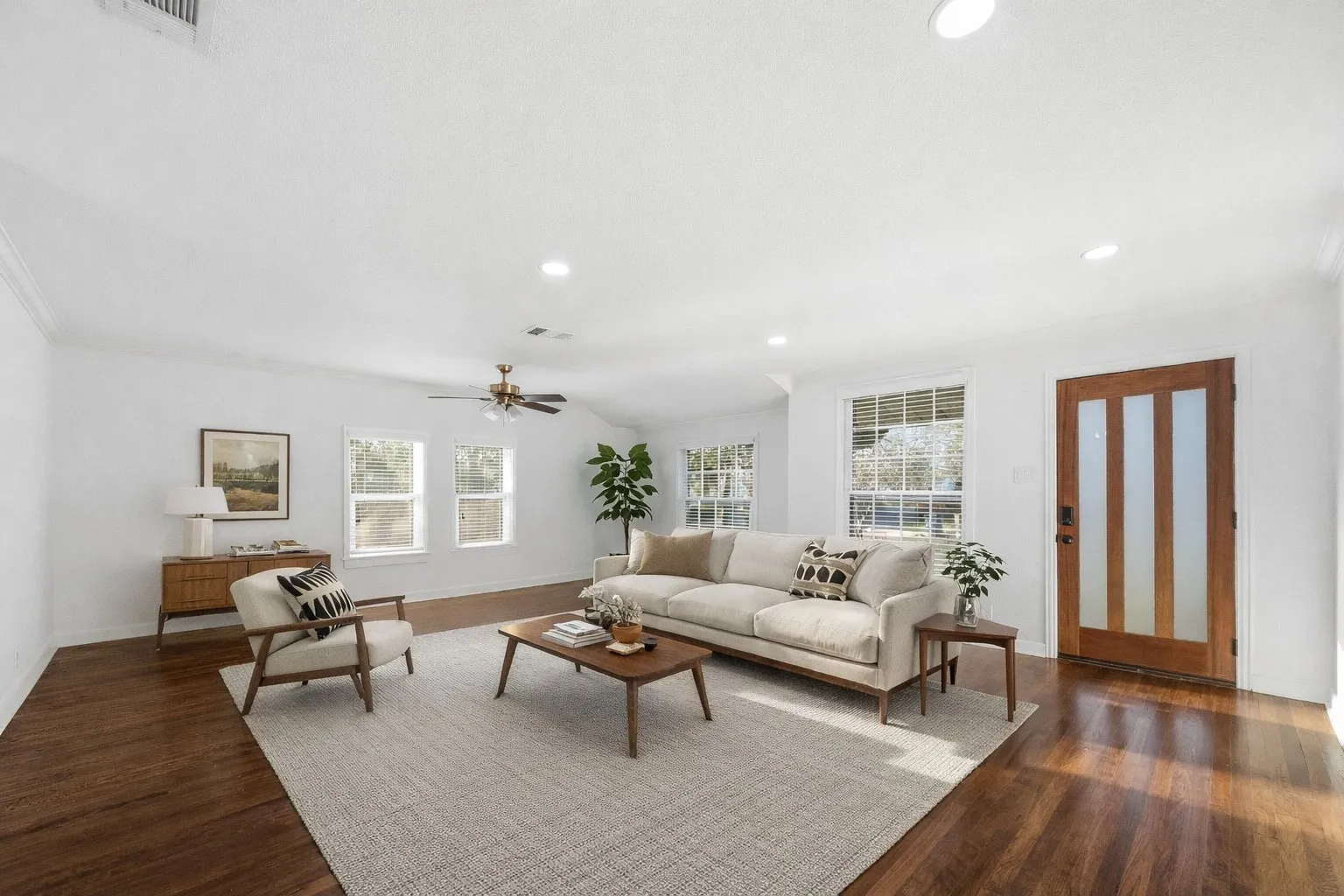 Spacious living area featuring wood-finish flooring, multiple windows with blinds, a ceiling fan, recessed lighting, and a solid wood entry door with frosted glass inserts - Virtually​​‌​​​​‌​​‌‌​‌‌​​​‌‌​‌​‌​‌​​​‌​​ staged