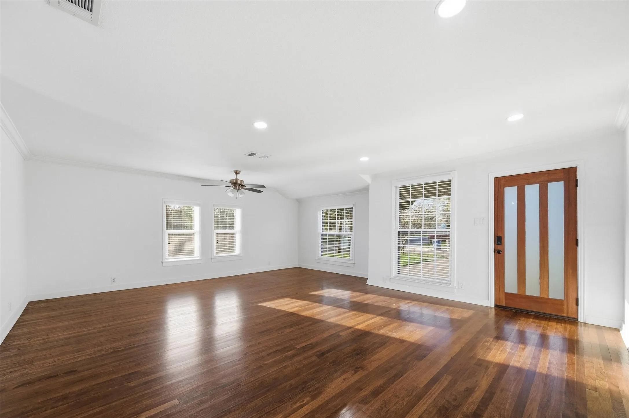 Unfurnished living room featuring crown molding, dark wood-style flooring, recessed lighting, and a ceiling fan