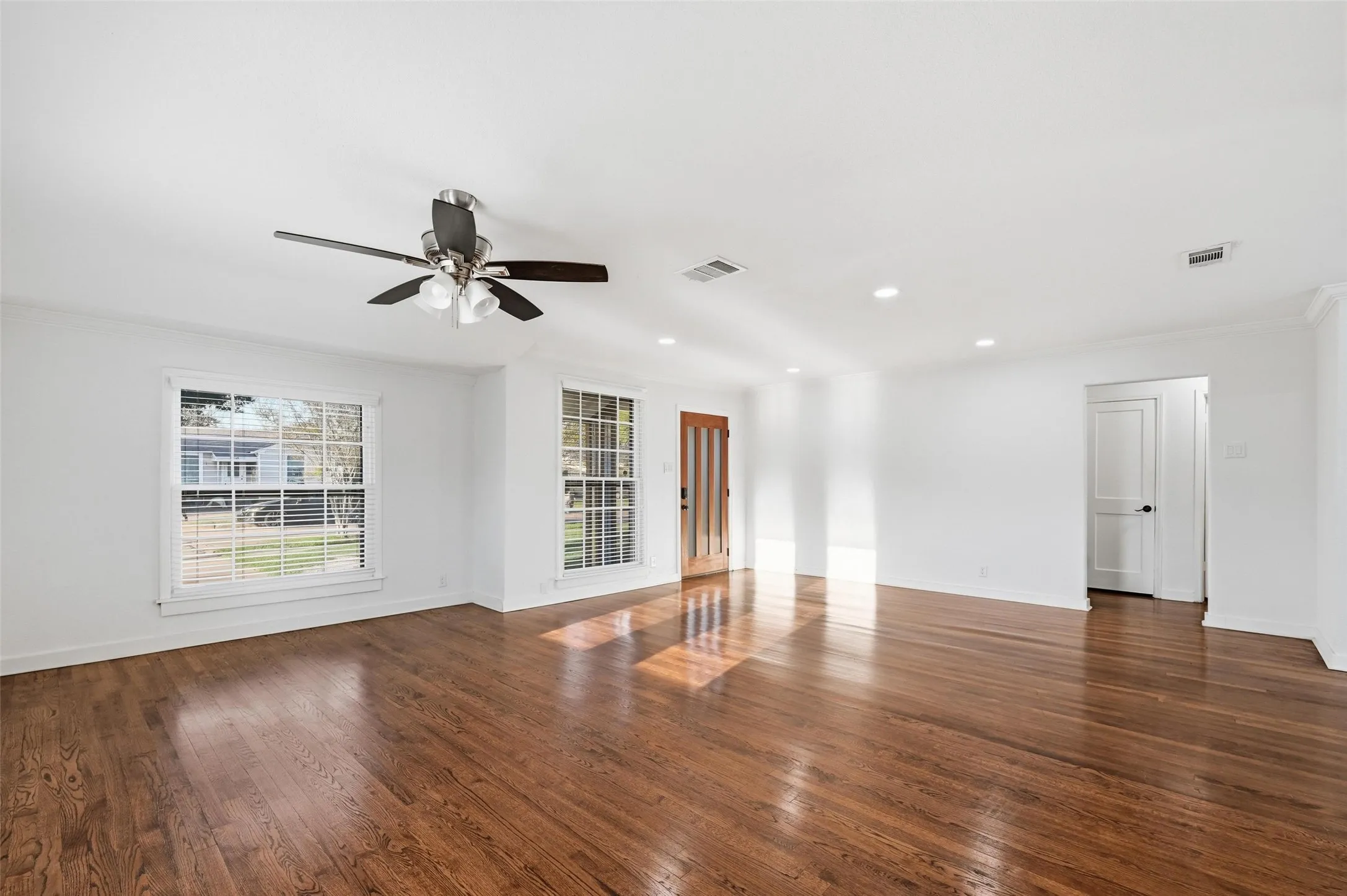 Empty room featuring dark wood-style flooring, ceiling fan, crown molding, and recessed lighting