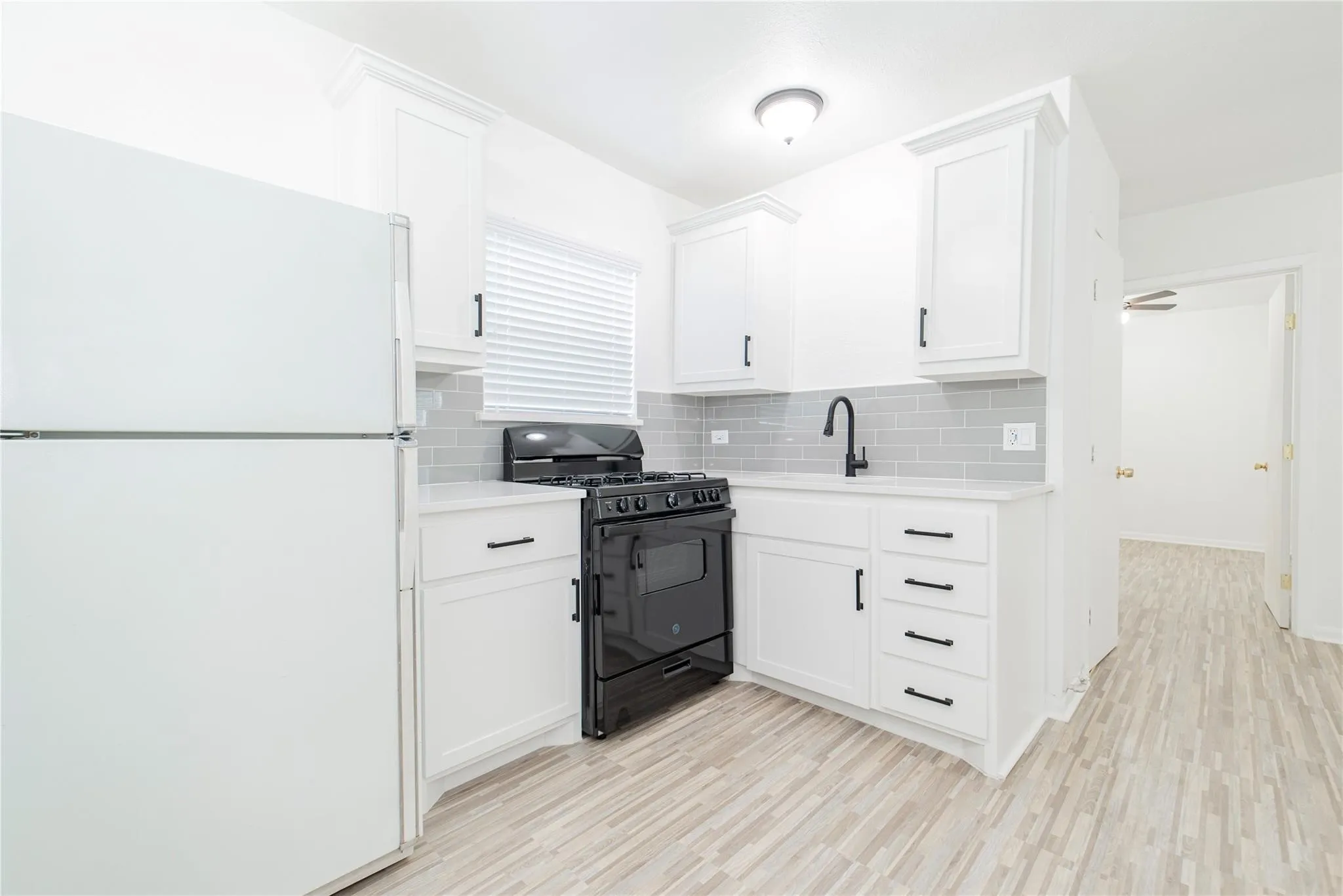 Kitchen with freestanding refrigerator, black range with gas cooktop, and white cabinetry
