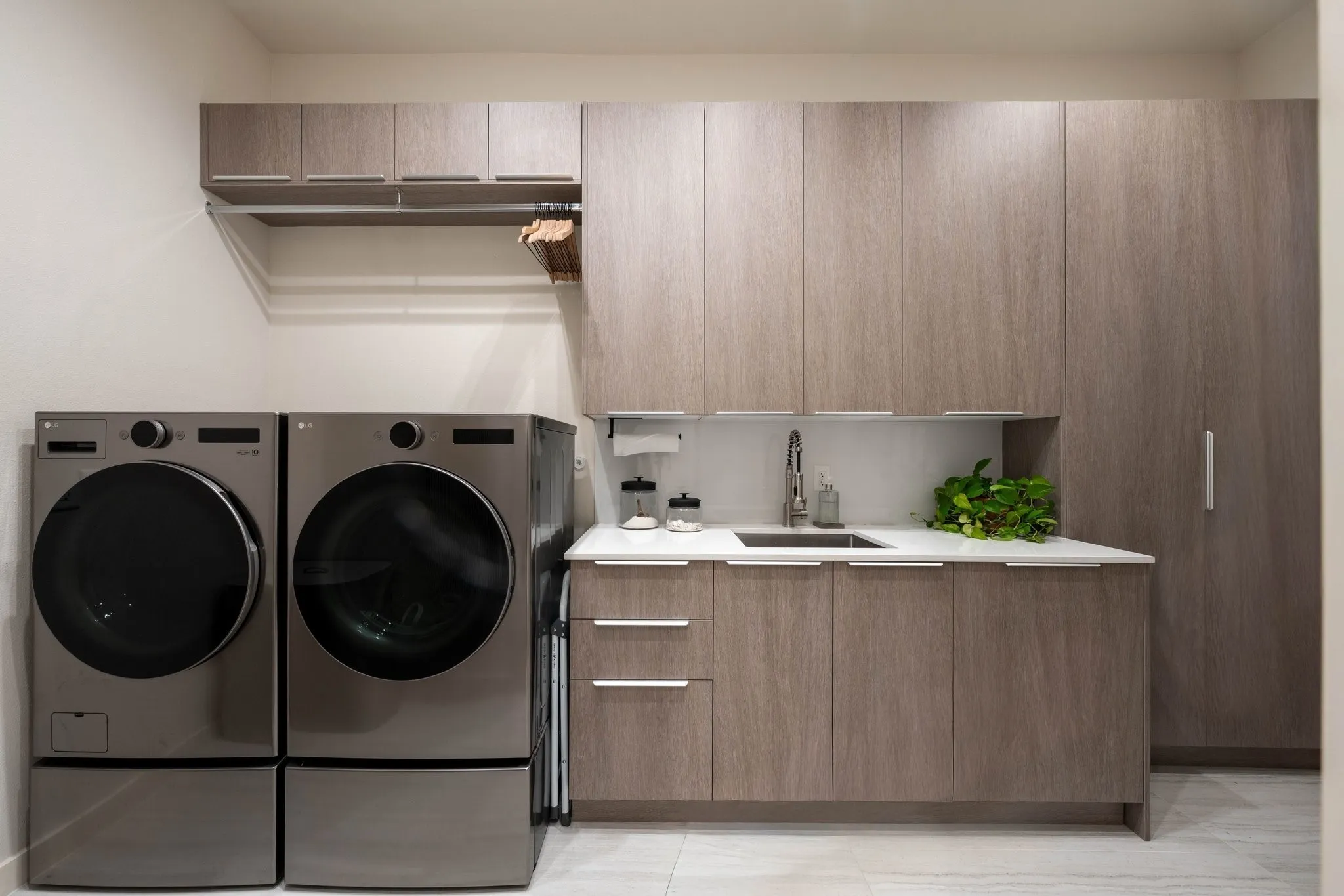 Laundry room featuring full size washer/dryer and hanging clothes dryer. Modern cabinets with lots of storage