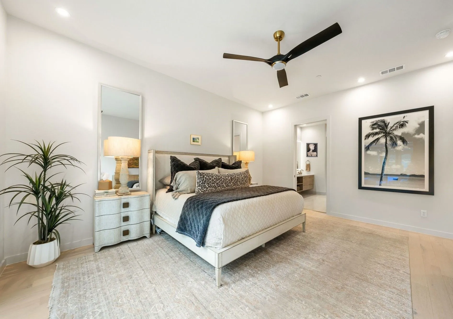 Large primary bedroom with light wood flooring, recessed lighting, ceiling fan, and ensuite bathroom