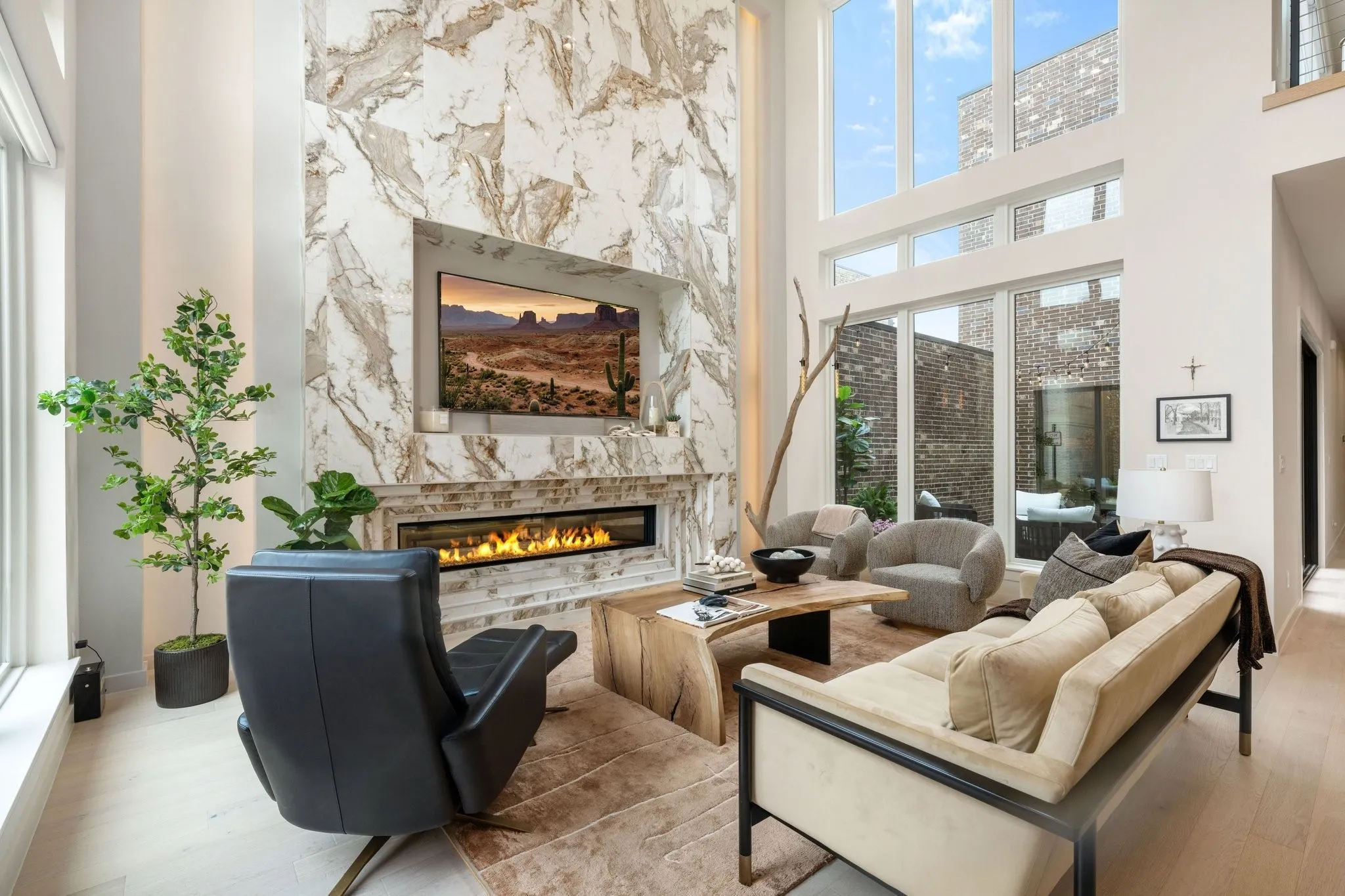 Living area with a high ceiling, large windows that allow for natural light, a glass covered fireplace, and wood finished floors
