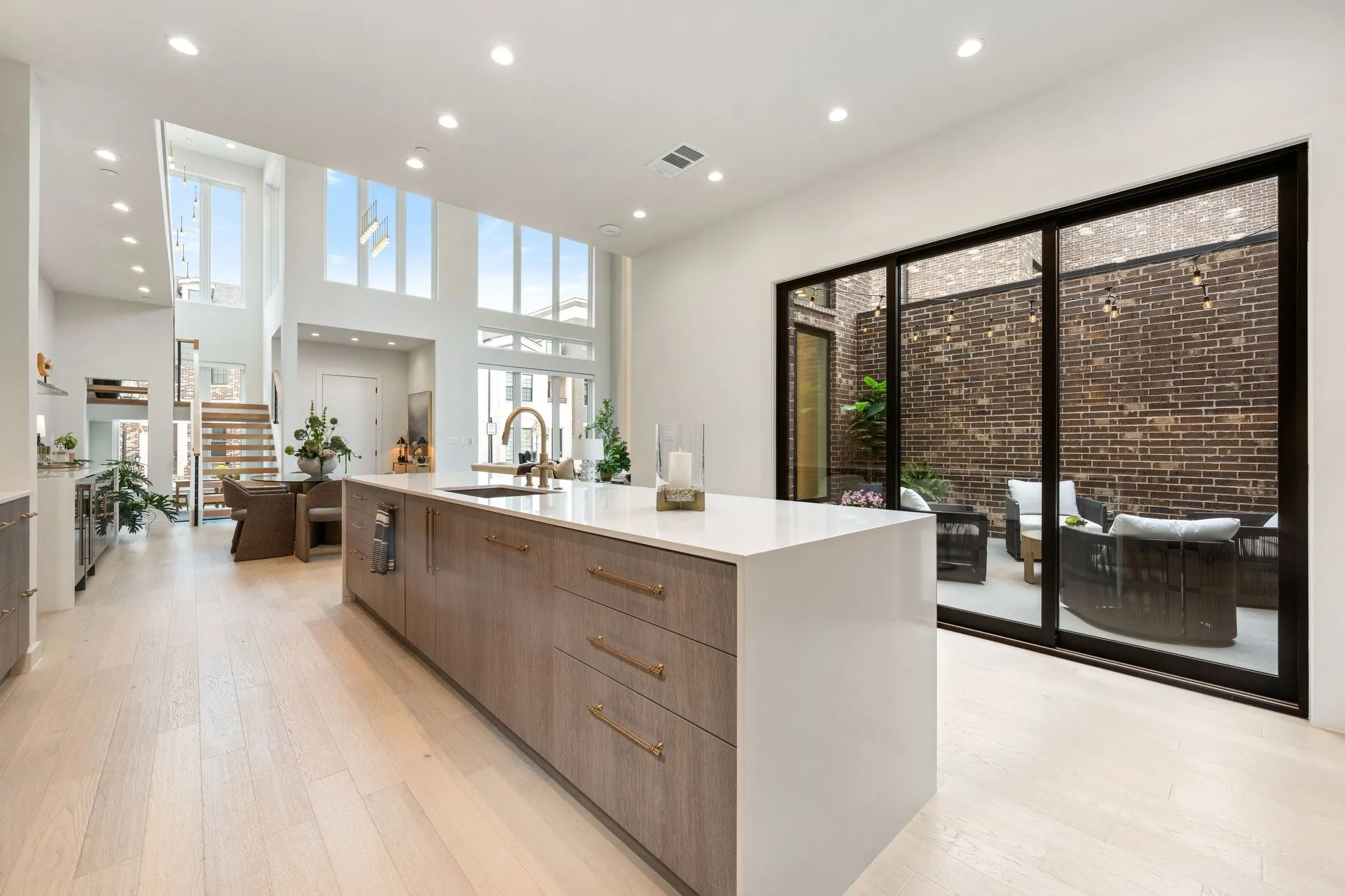 Kitchen featuring modern cabinets, an island with waterfall quartz, open to courtyard