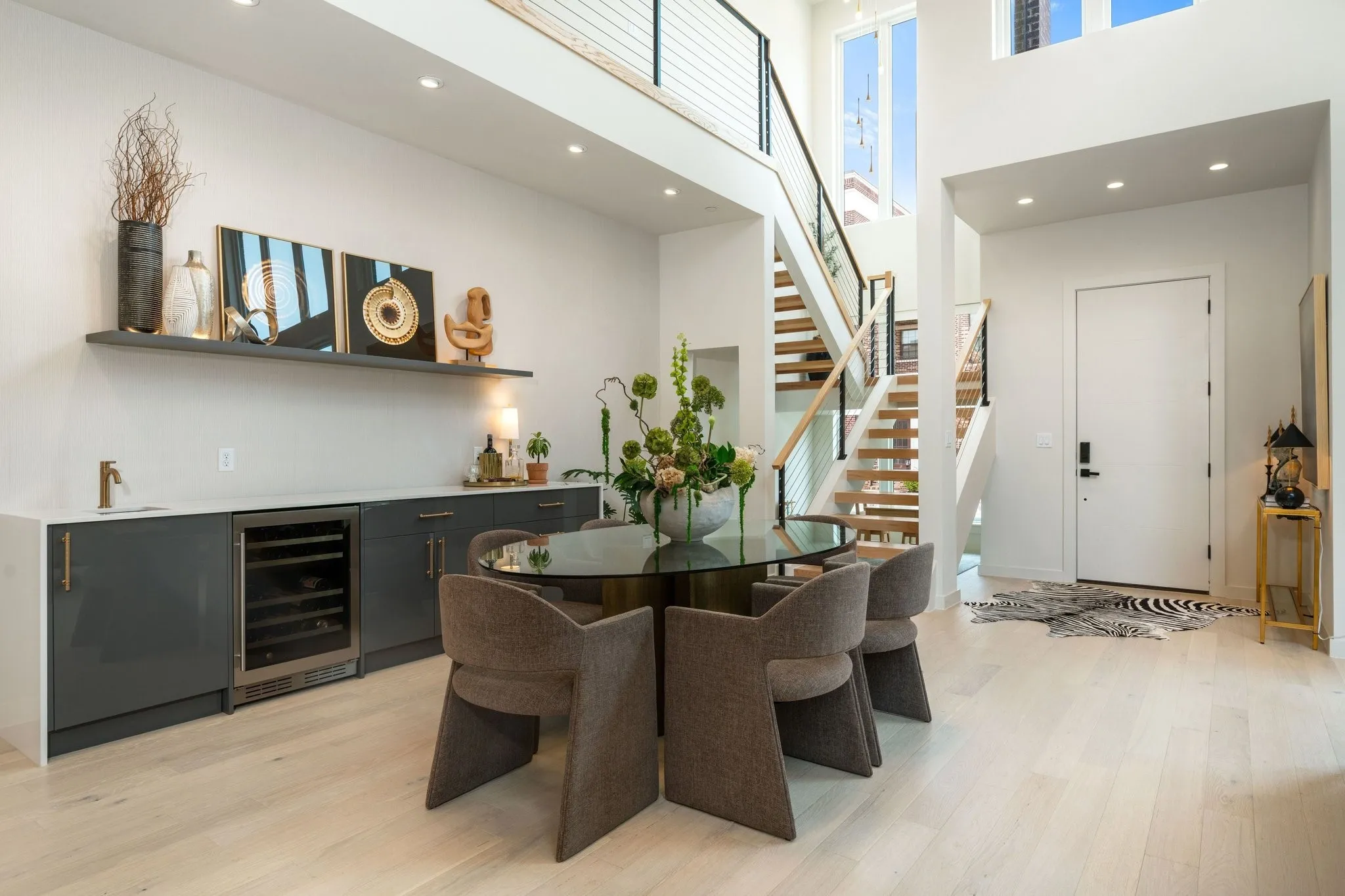 Dining space with wine cooler, floating oak stairs, 20' high ceiling, and quartz bar with sink