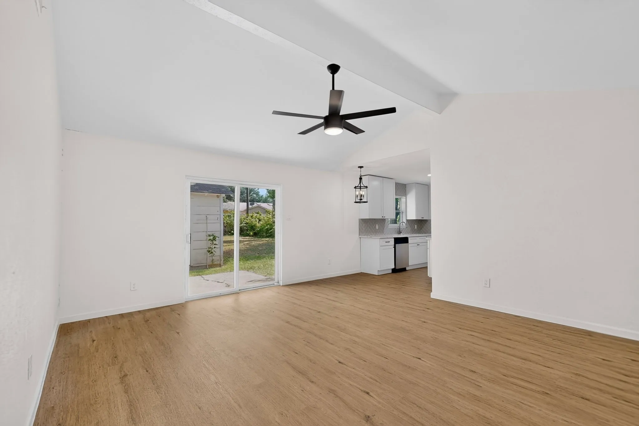 Bright interior with vaulted ceilings, wood-finish flooring, and a contemporary ceiling fan