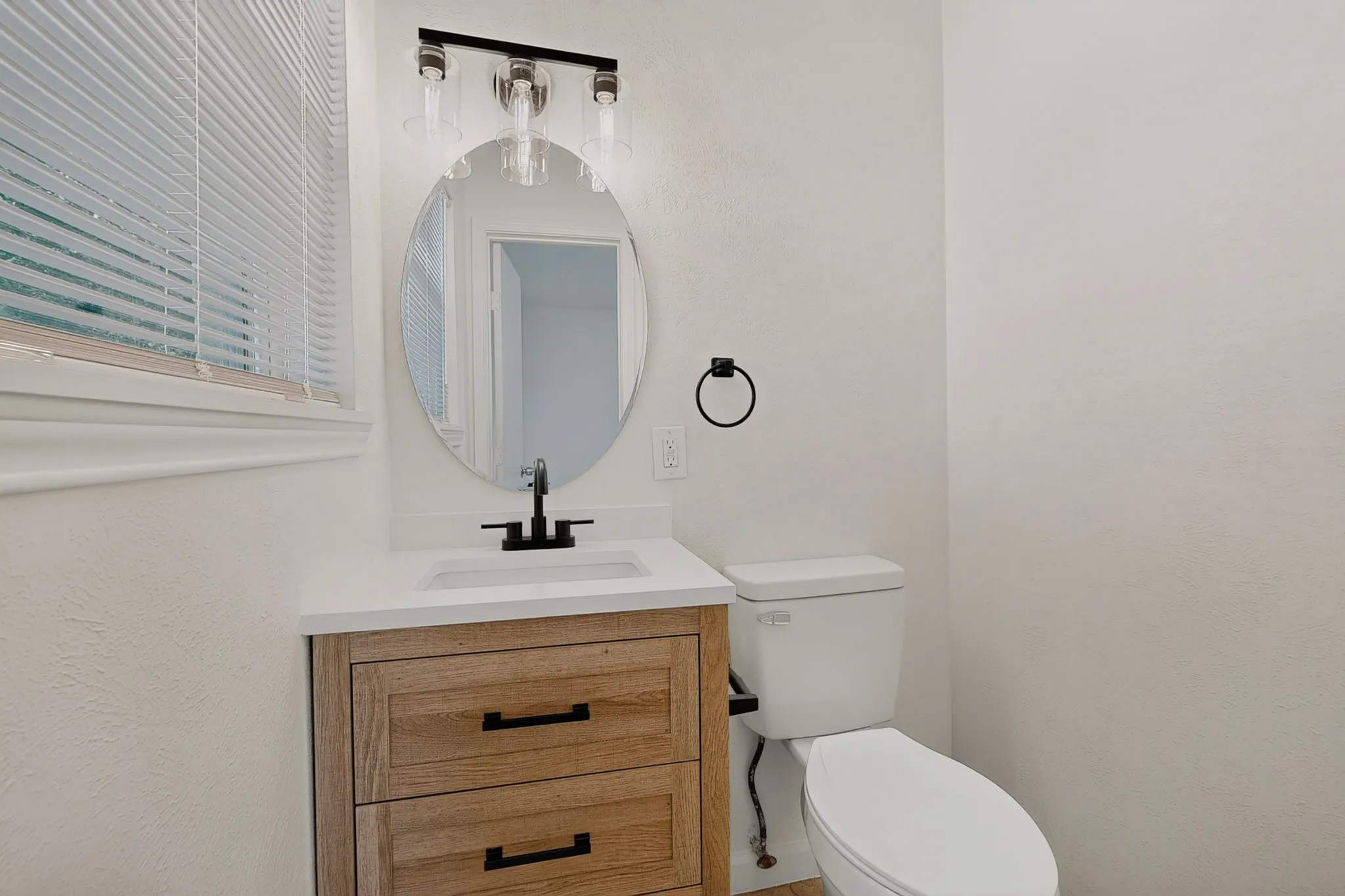 White-painted bathroom featuring a wood-finish vanity with a white countertop and rectangular sink