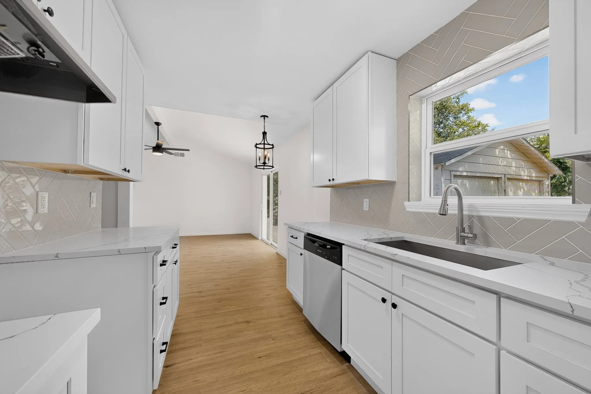 Contemporary kitchen featuring white cabinetry, quartz-finish countertops, stainless steel appliances, and a herringbone-patterned tile backsplash